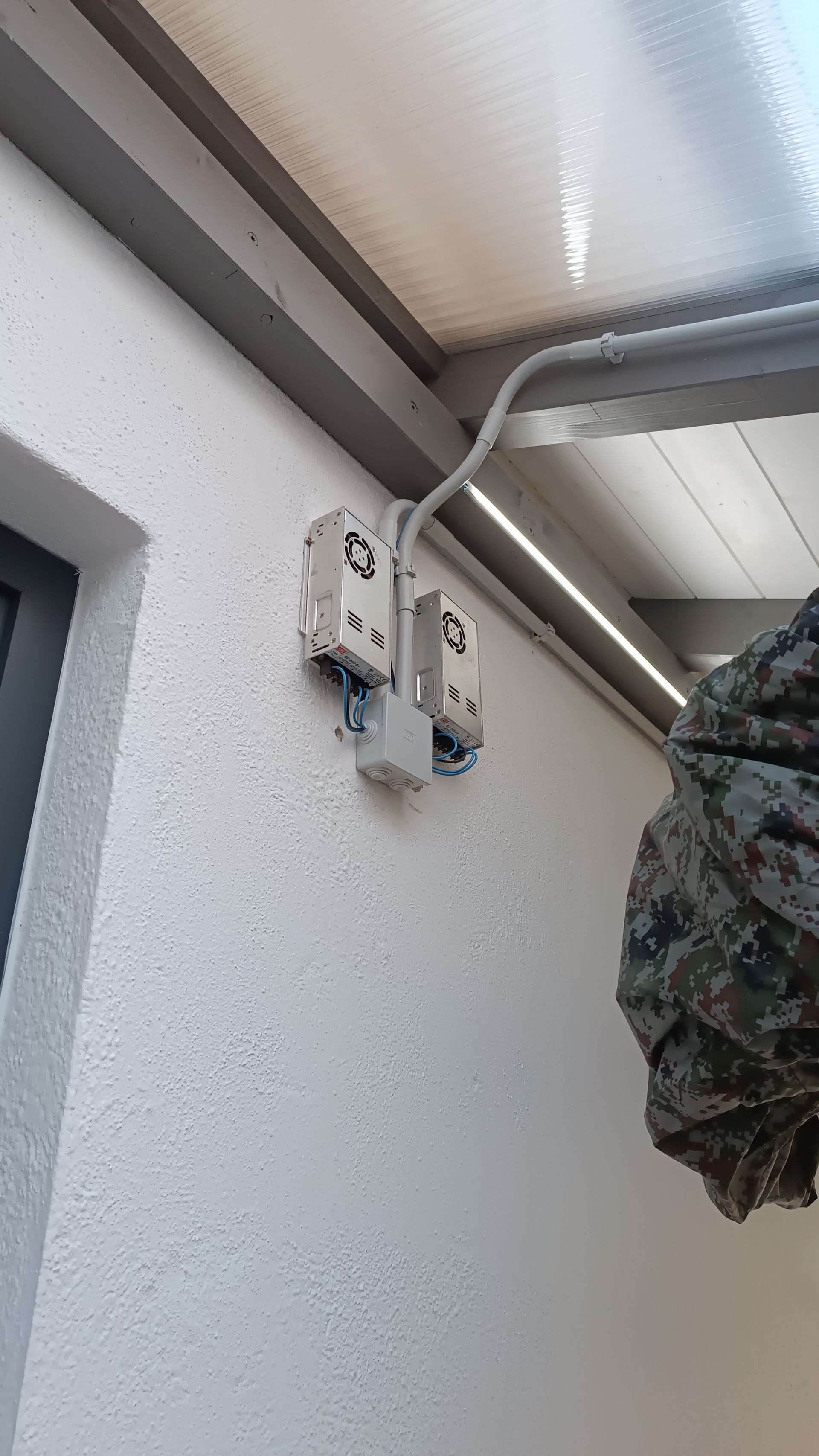 Un primer plano de una pared con cables eléctricos colgando de ella.