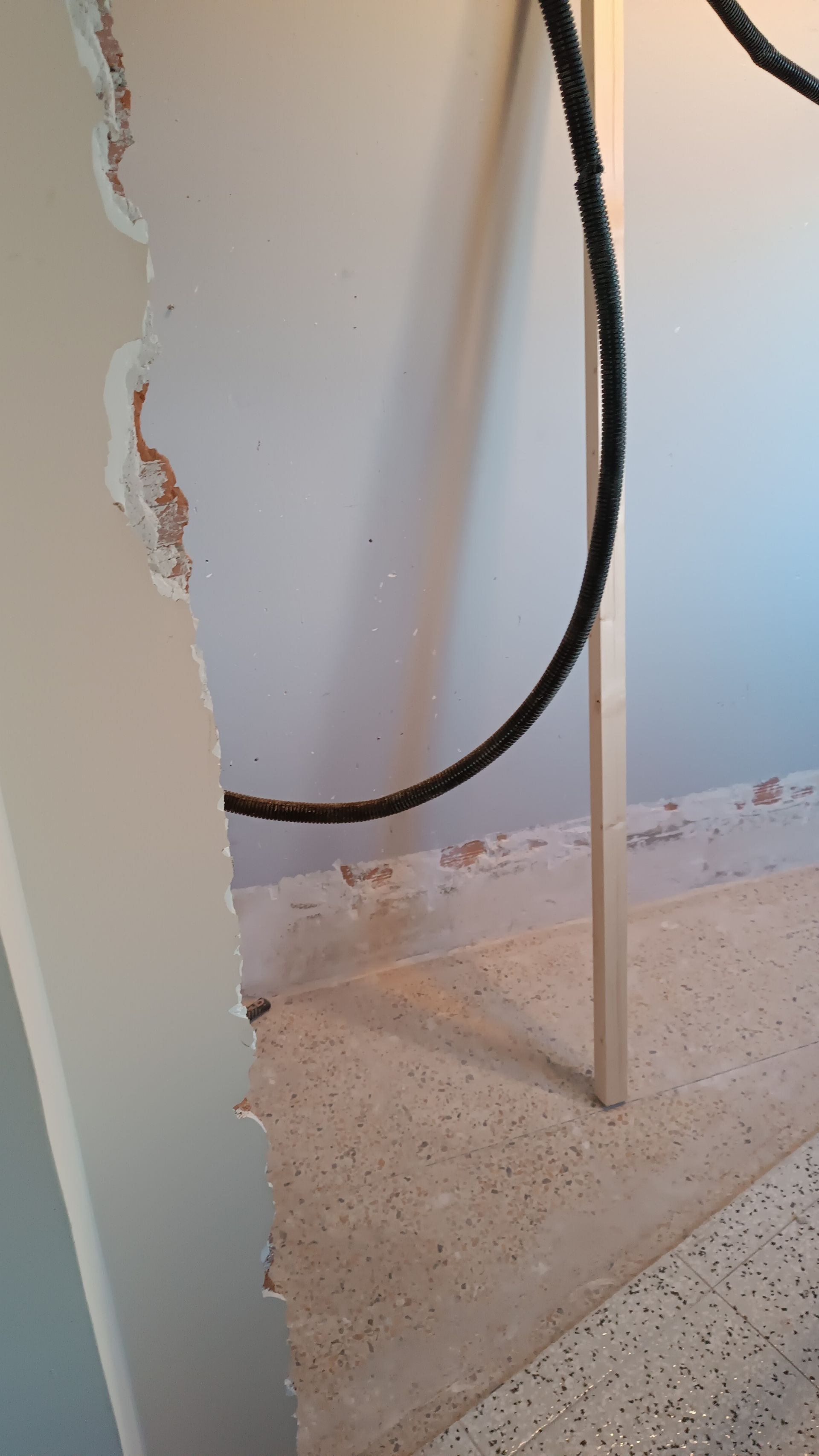 Una manguera negra cuelga de una pared en una habitación.