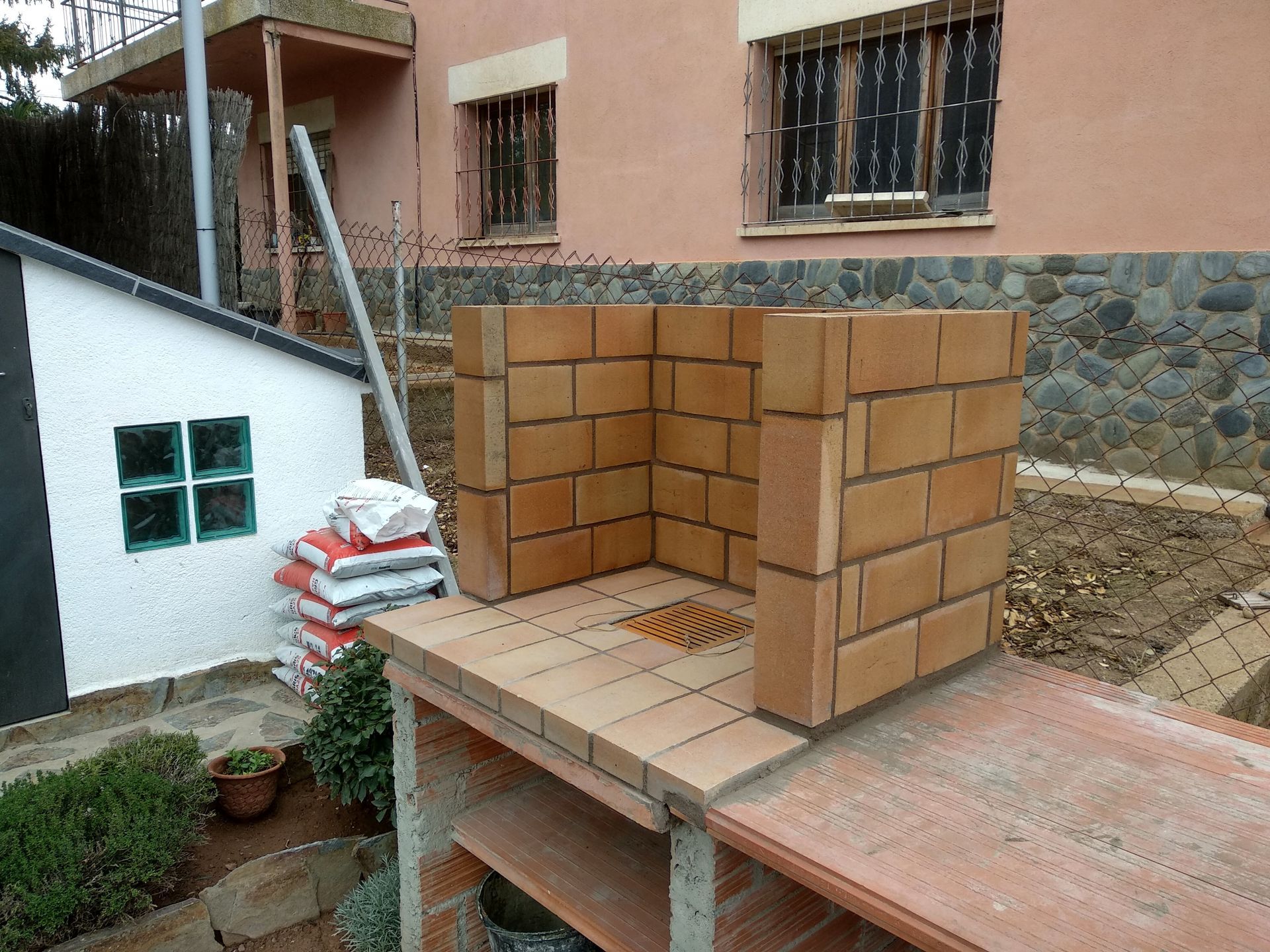 Se está construyendo un muro de ladrillos frente a una casa.