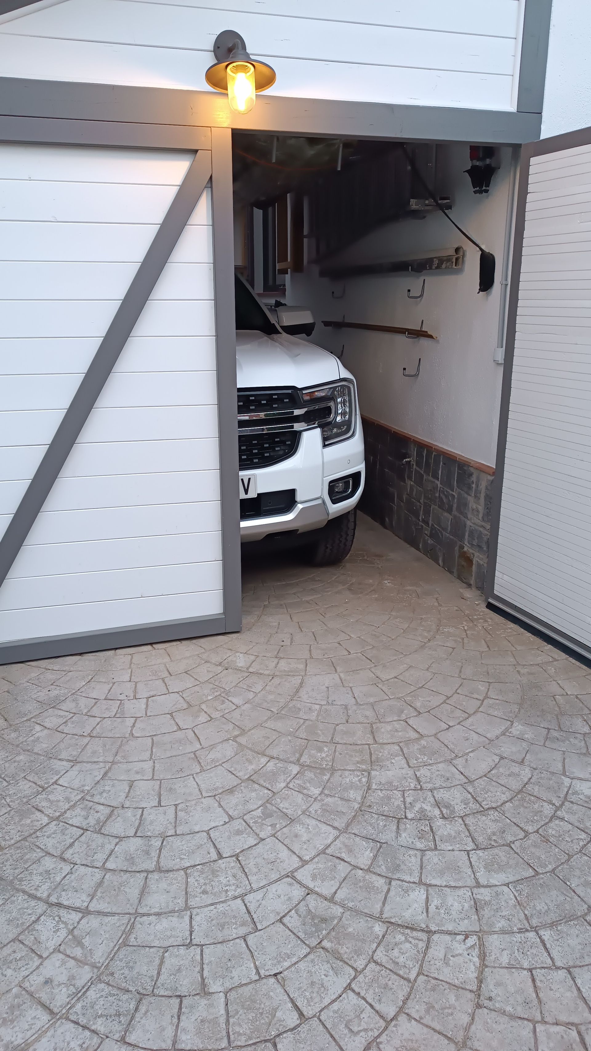 Un todoterreno blanco está estacionado en un garaje con la puerta abierta.