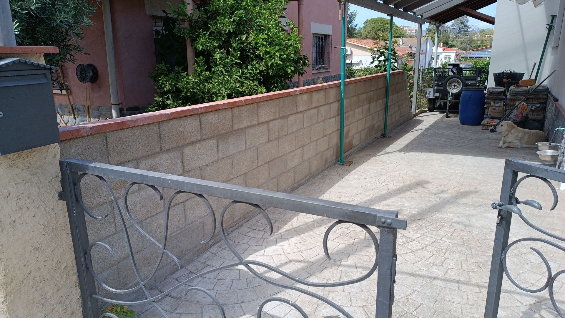 Una pared de ladrillos con una puerta de hierro forjado delante.