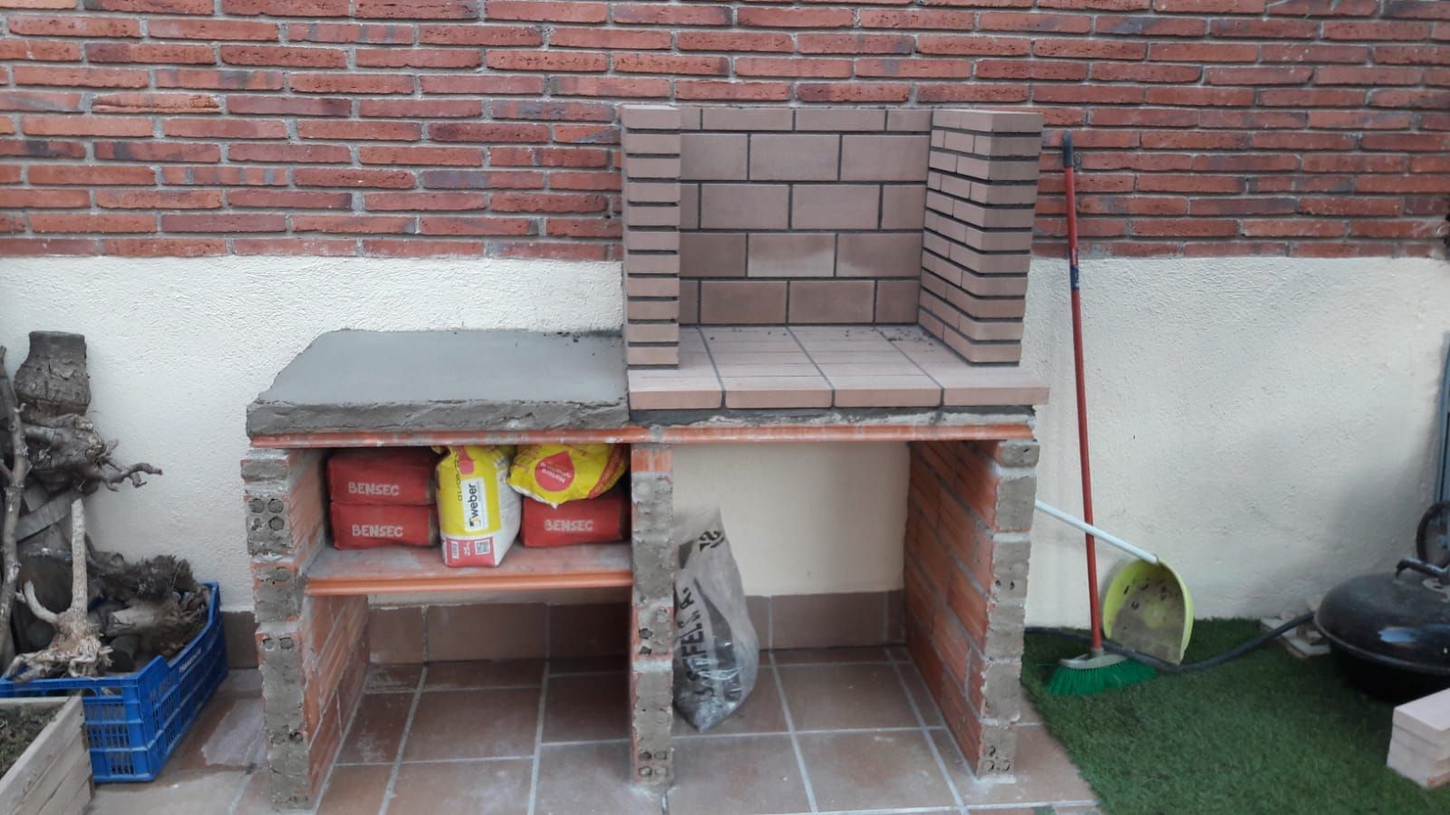 Se está construyendo una barbacoa de ladrillo en un patio trasero.