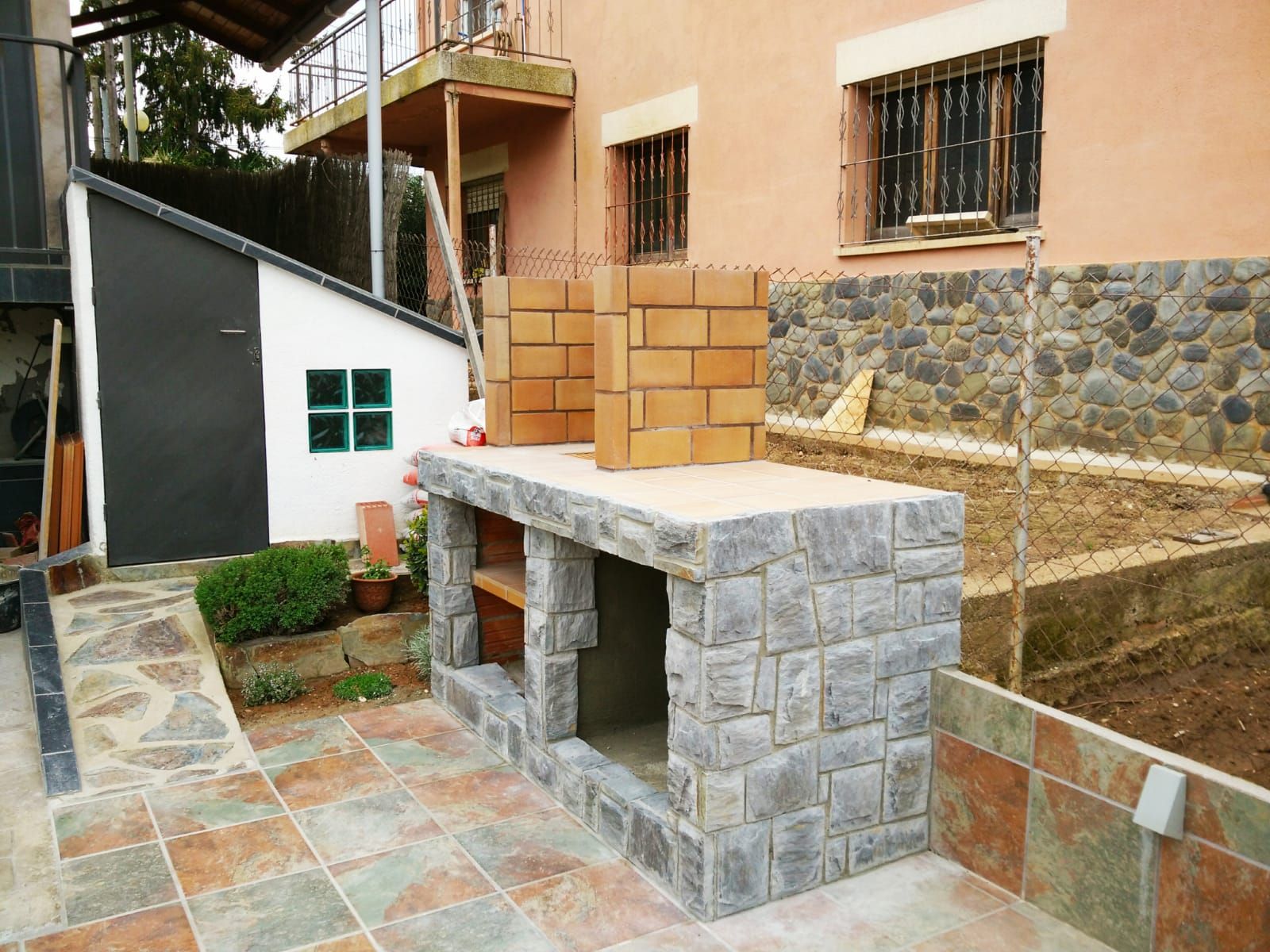 Se está construyendo un muro de ladrillos frente a una casa.