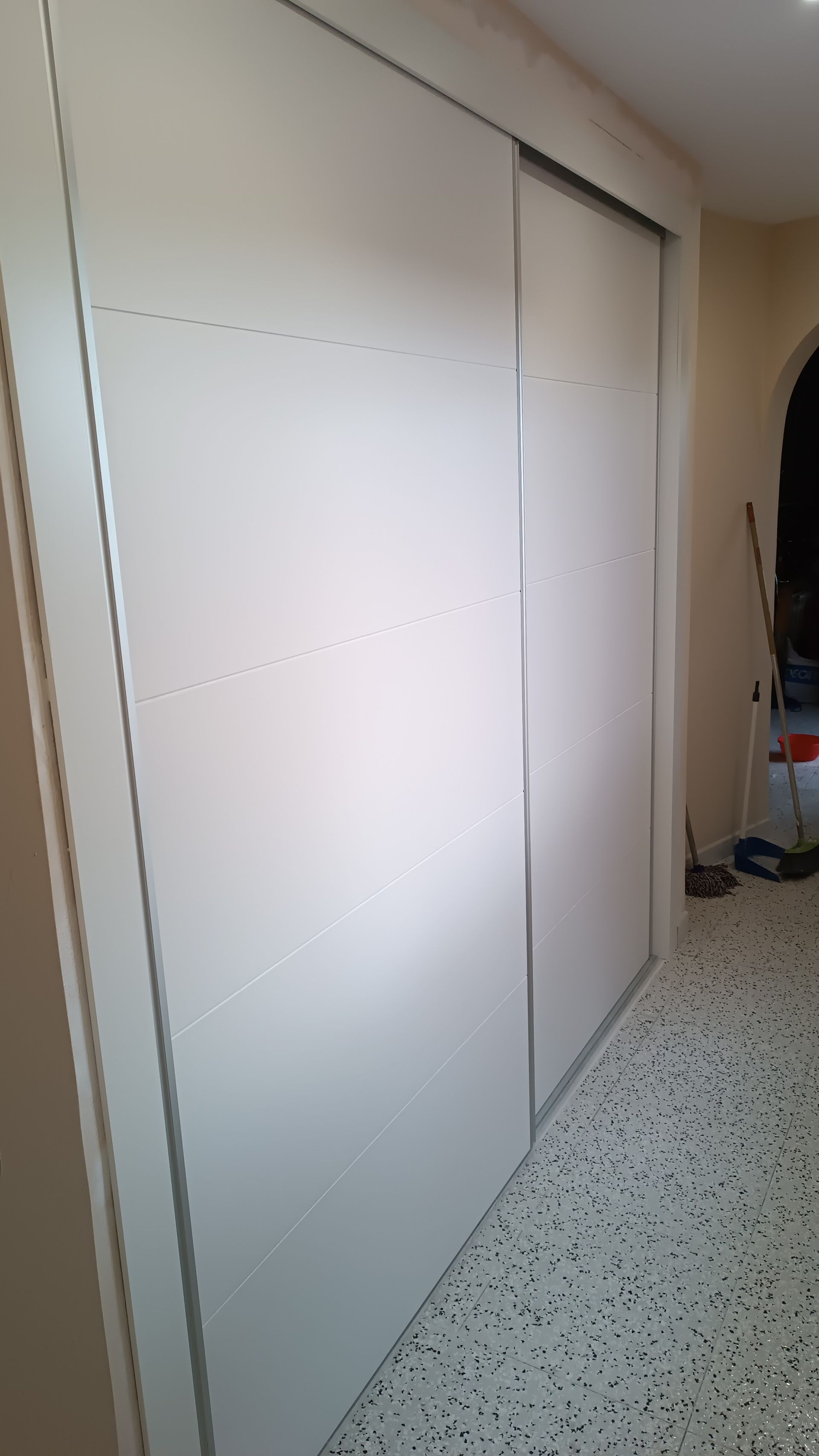 Un pasillo con puertas correderas y una pared blanca.