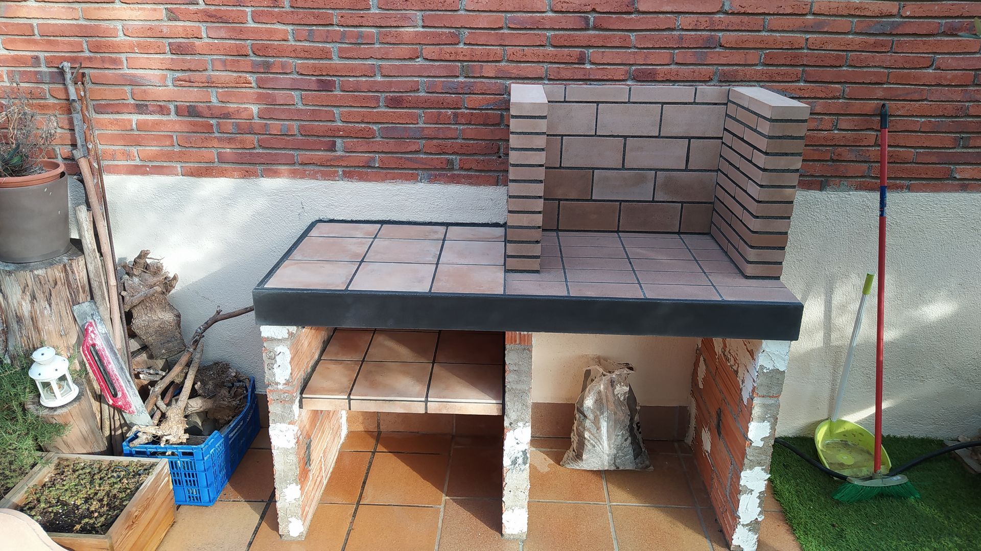 Una escoba está sentada junto a una pared de ladrillos.