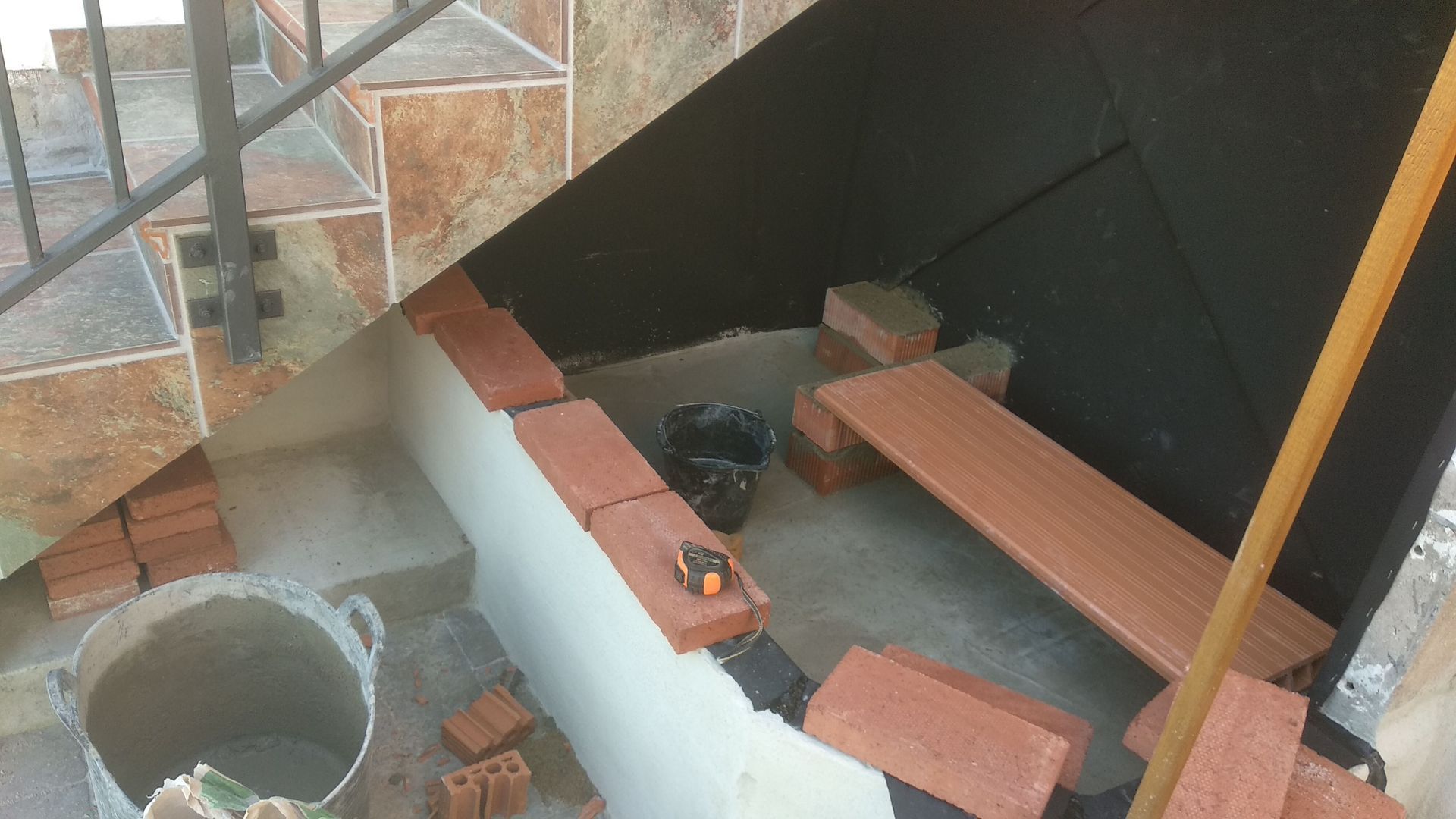 Se está construyendo un banco de ladrillo debajo de unas escaleras.
