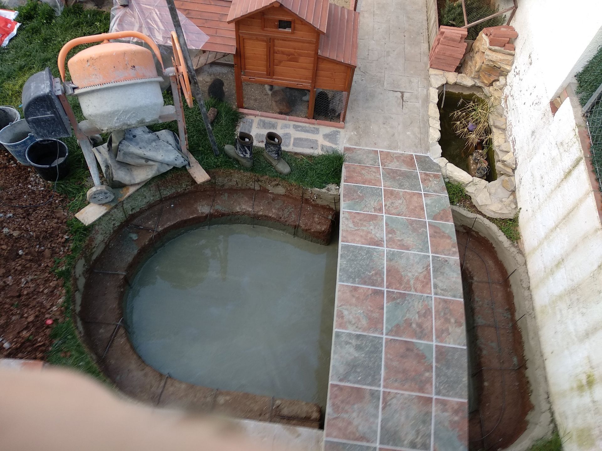 Una vista aérea de un pequeño estanque con una casa de madera al fondo.
