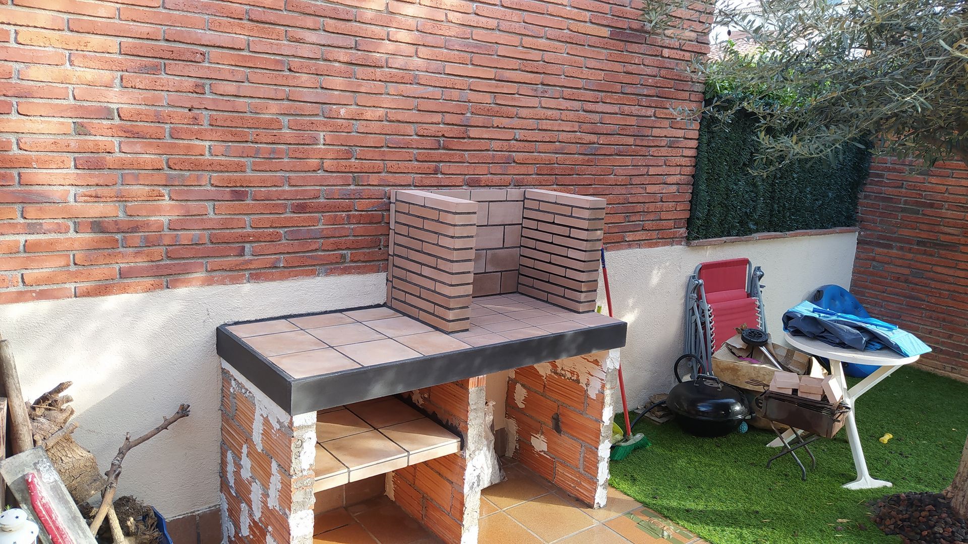 Una pared de ladrillos con una mesa y sillas delante de ella.