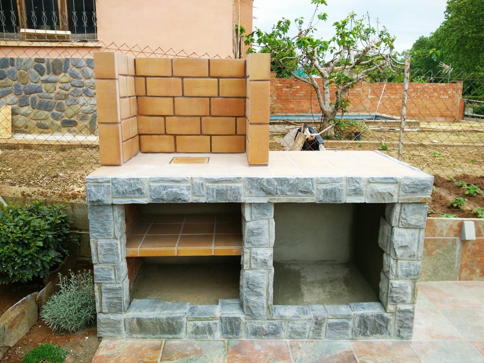 Se está construyendo un muro de ladrillos frente a una casa.