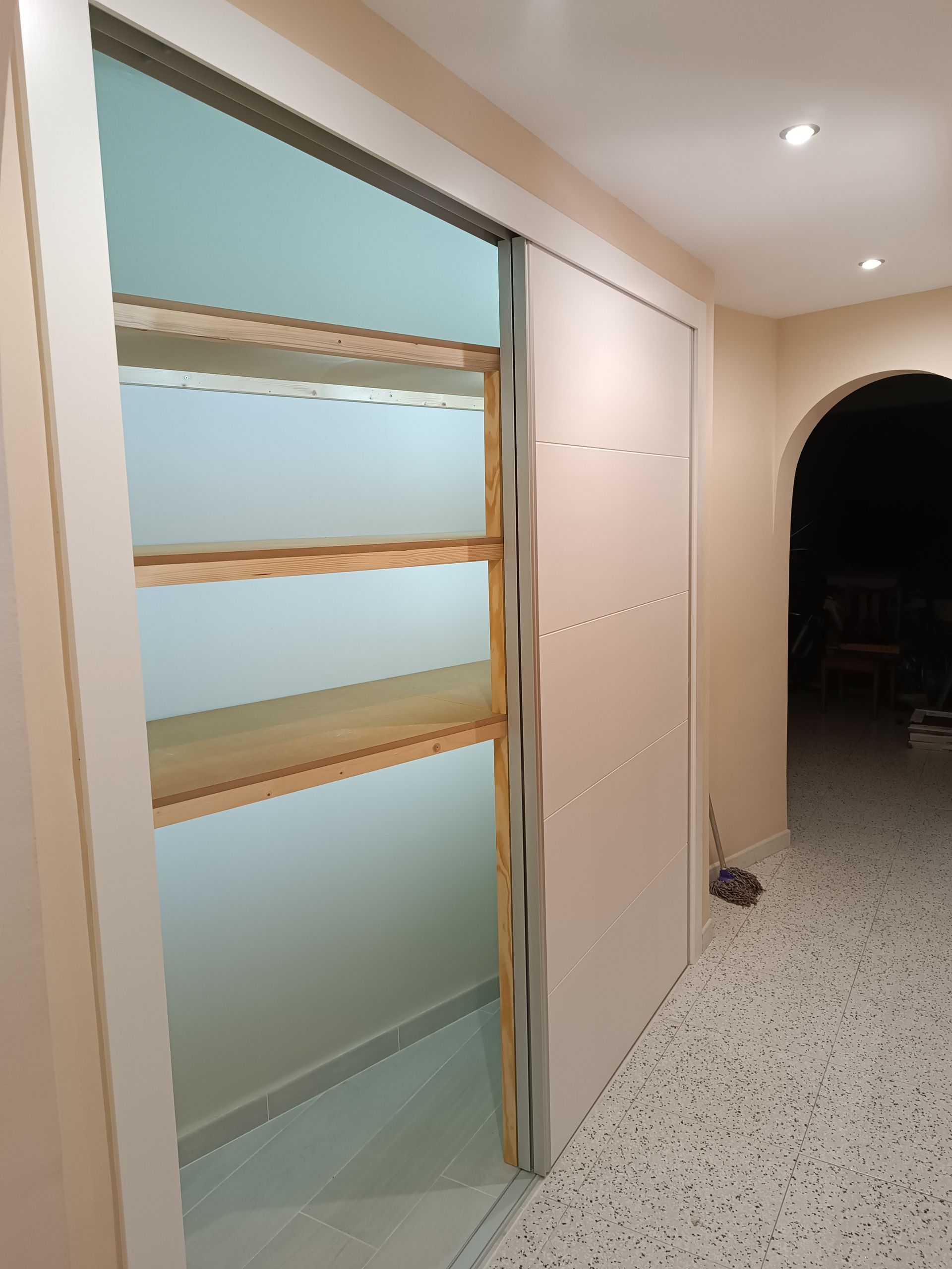 Un pasillo con una puerta corrediza de vidrio y estantes.