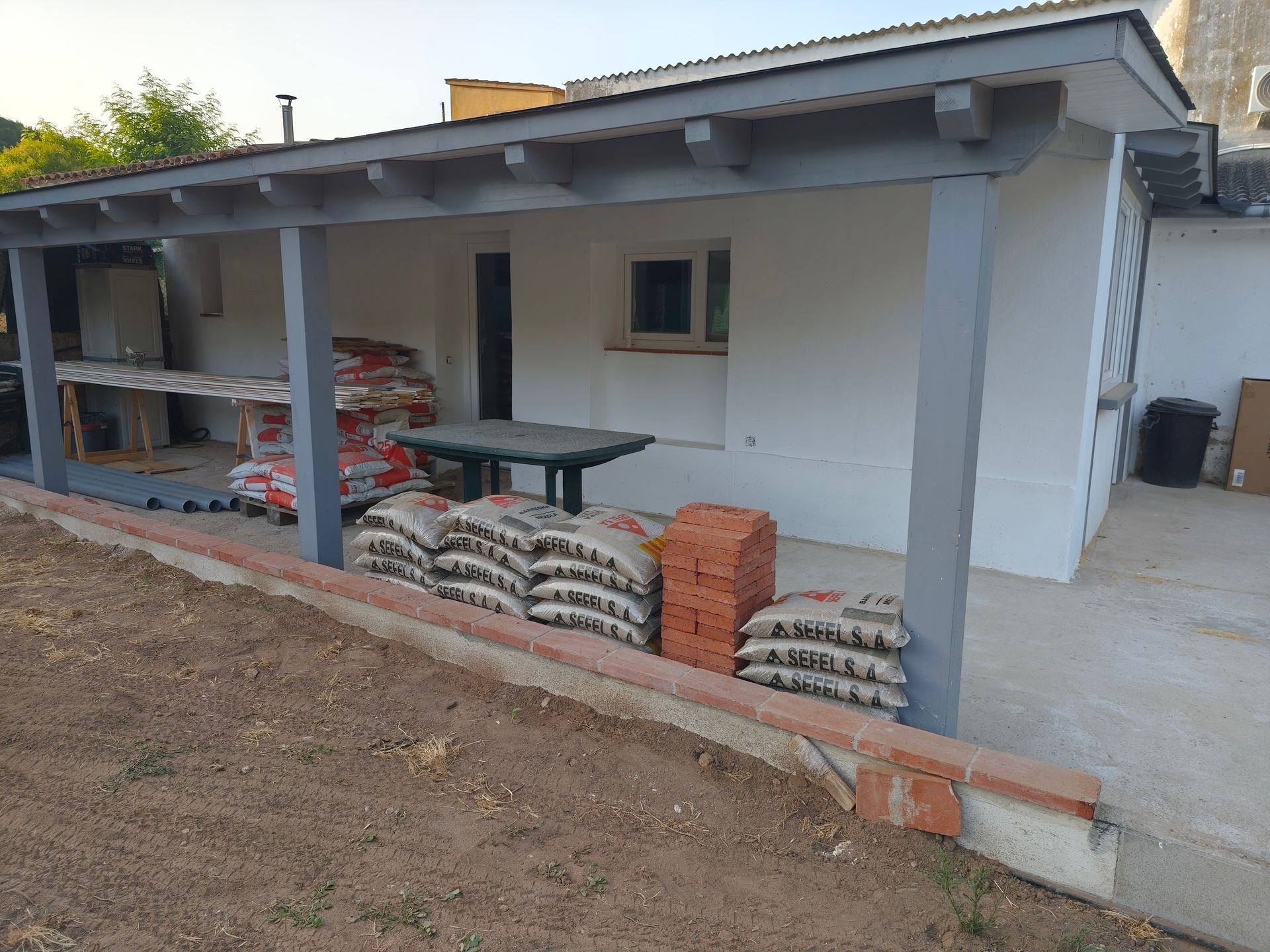 Un edificio blanco con un porche cubierto y ladrillos en el lateral.