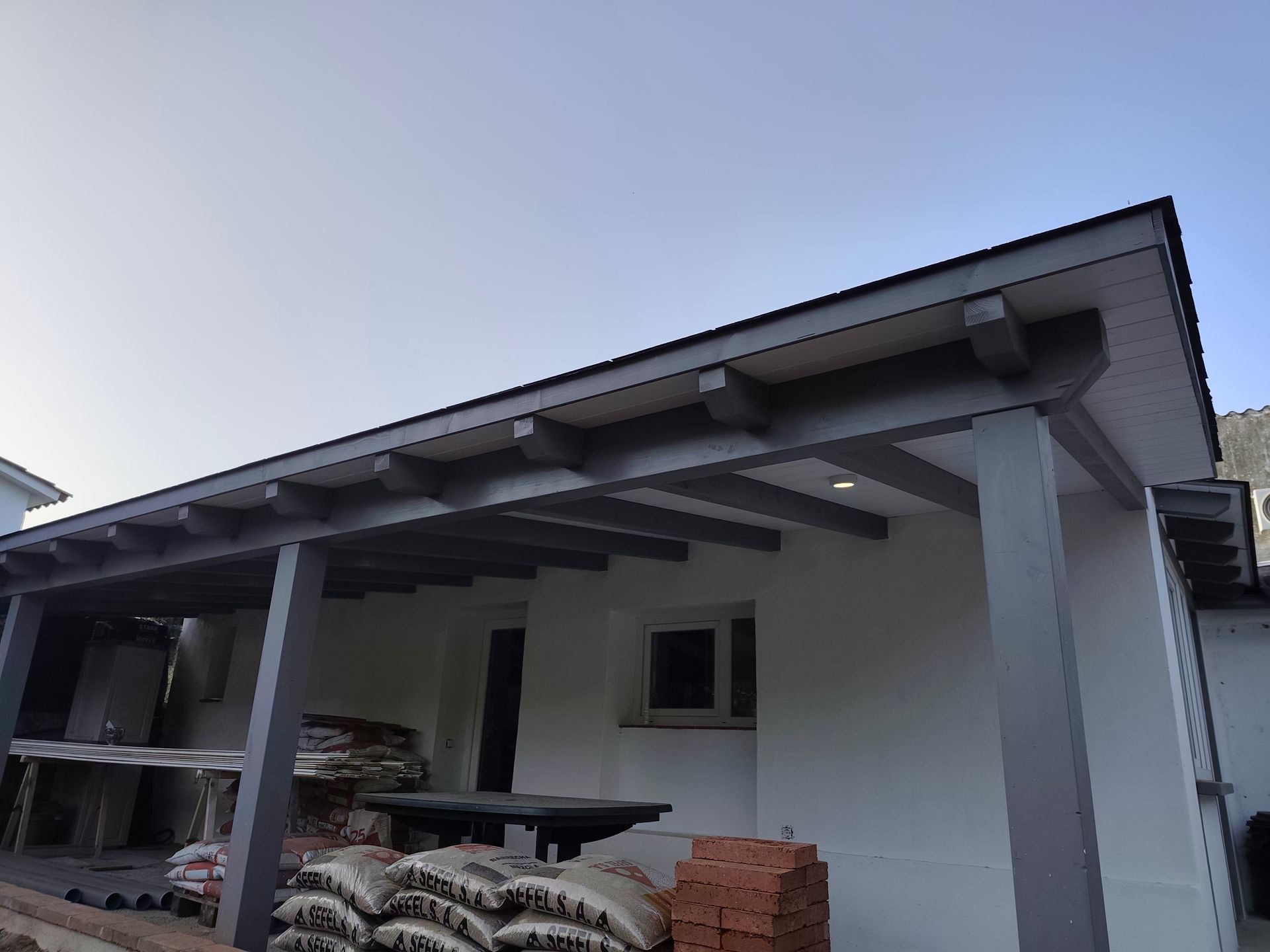 Una casa con un porche y un montón de bolsas de cemento en el suelo.