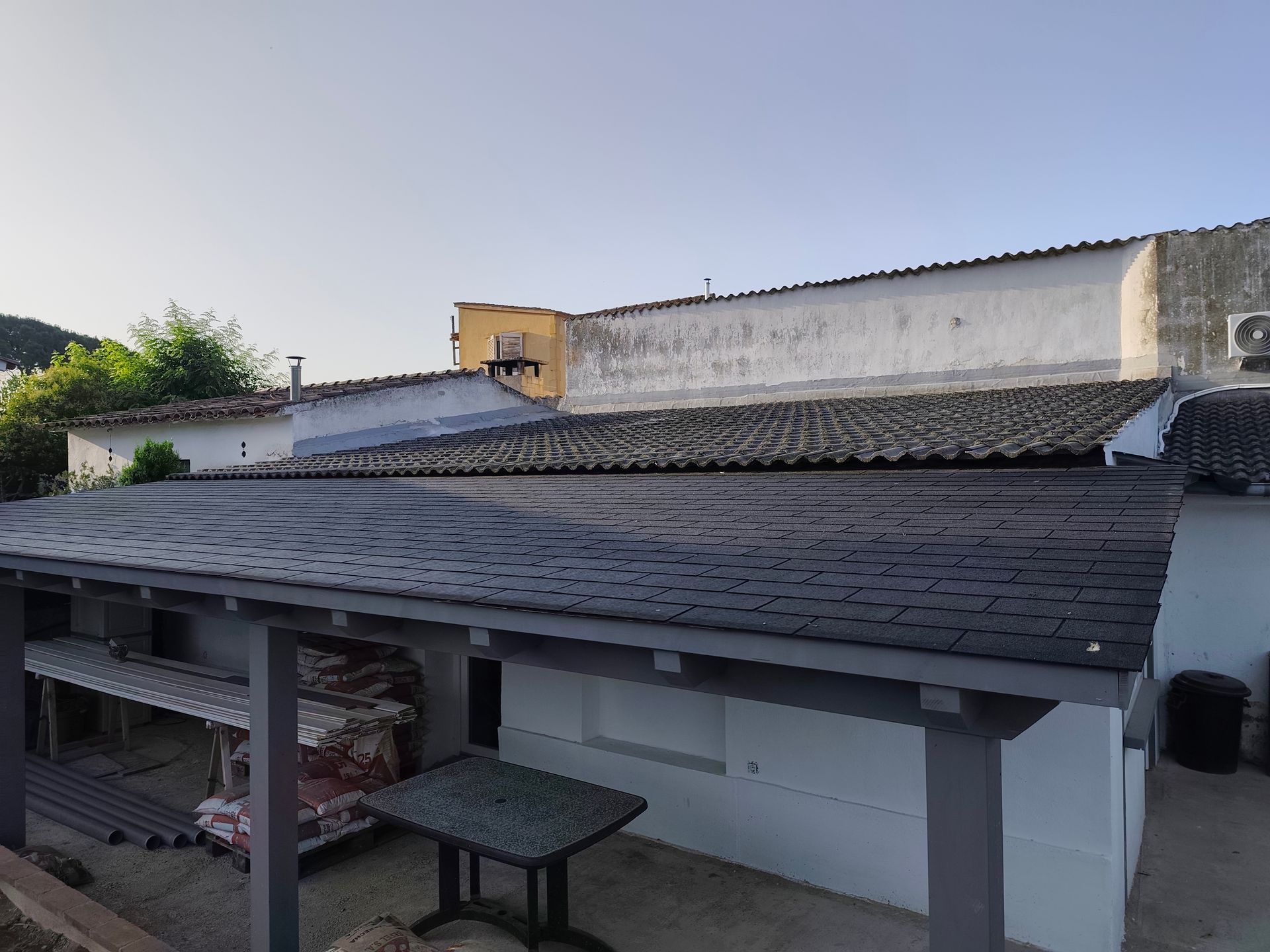 Hay una mesa y sillas debajo del techo de un edificio.