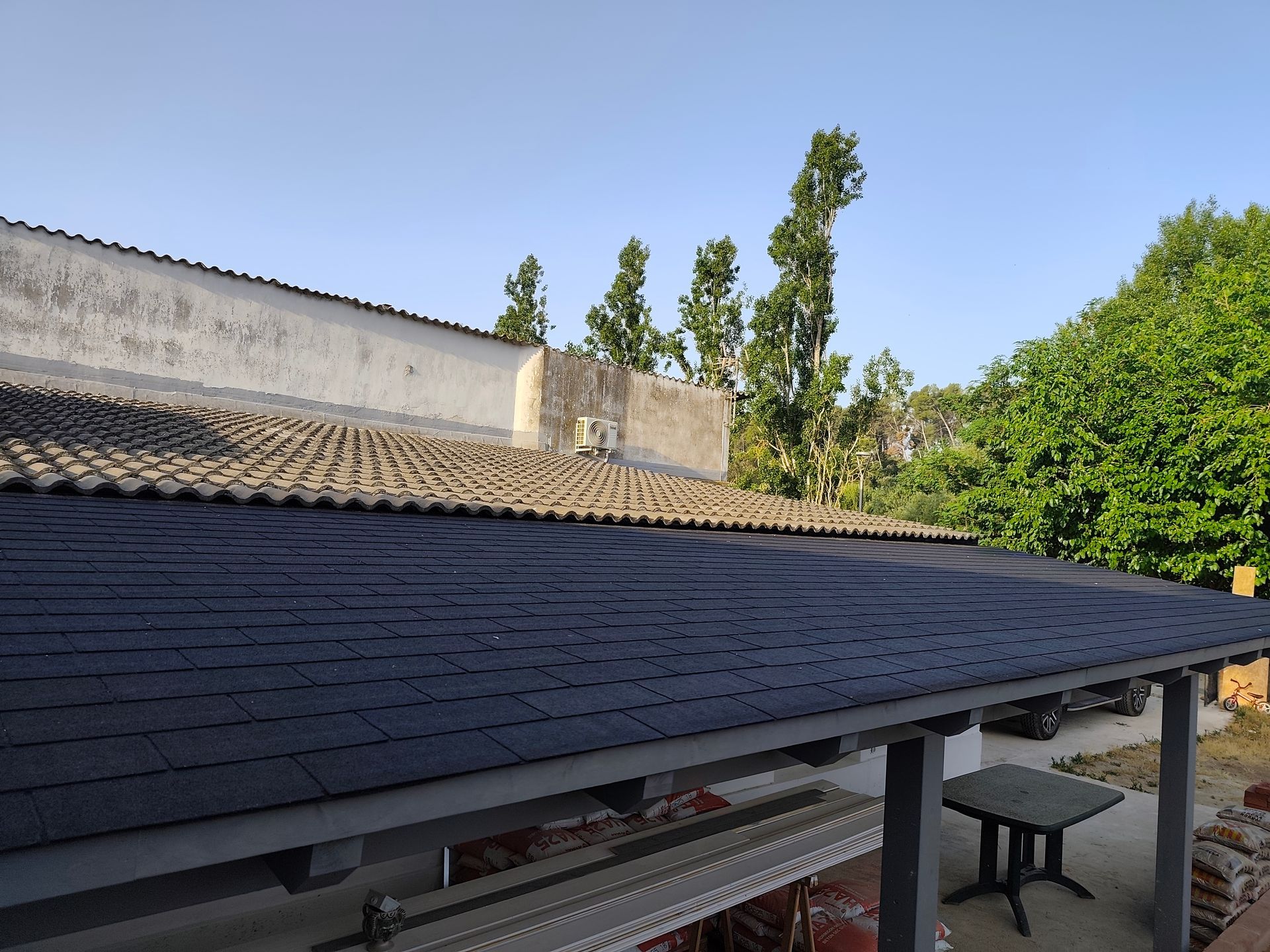 Un techo con una mesa debajo y árboles al fondo.