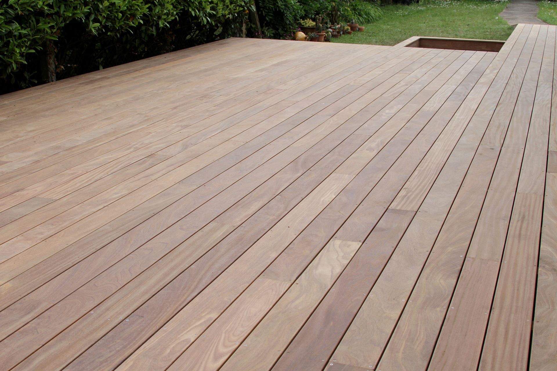 De larges planches de bois bordent une cour gazonnée et des arbres.