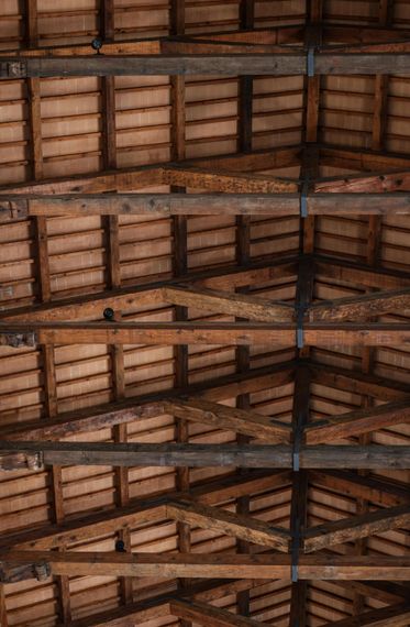 Intérieur d'une grange en bois avec charpente apparente, baigné par la douce lumière du jour.