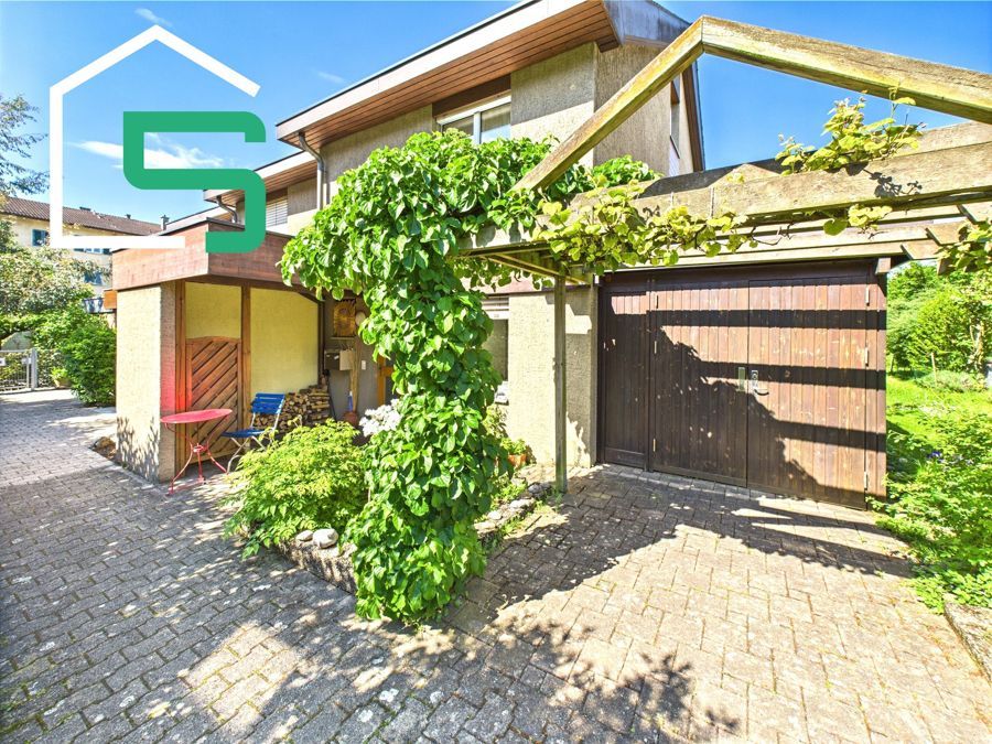 Hausaußenansicht mit gemauerter Auffahrt, Garage und Kletterpflanzen.