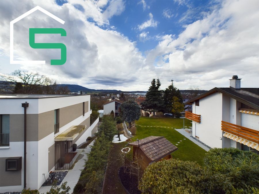 Moderne Häuser mit Grünflächen, Blick auf die Stadt unter bewölktem Himmel.