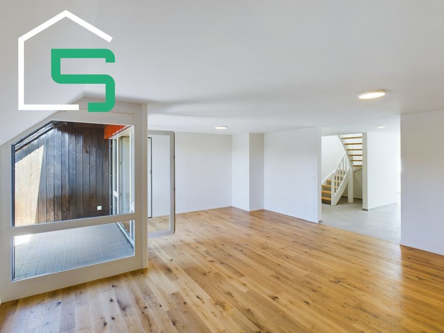 Geräumiger Innenraum mit Hartholzböden und einer Treppe; in der oberen linken Ecke befindet sich ein Hauslogo.
