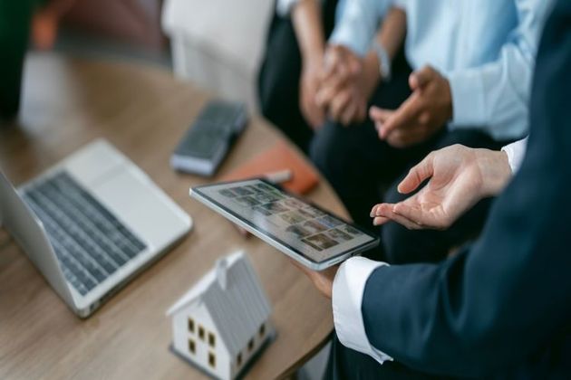 Ein Immobilienmakler in Olten zeigt Kunden Objekte auf einem Tablet. 
