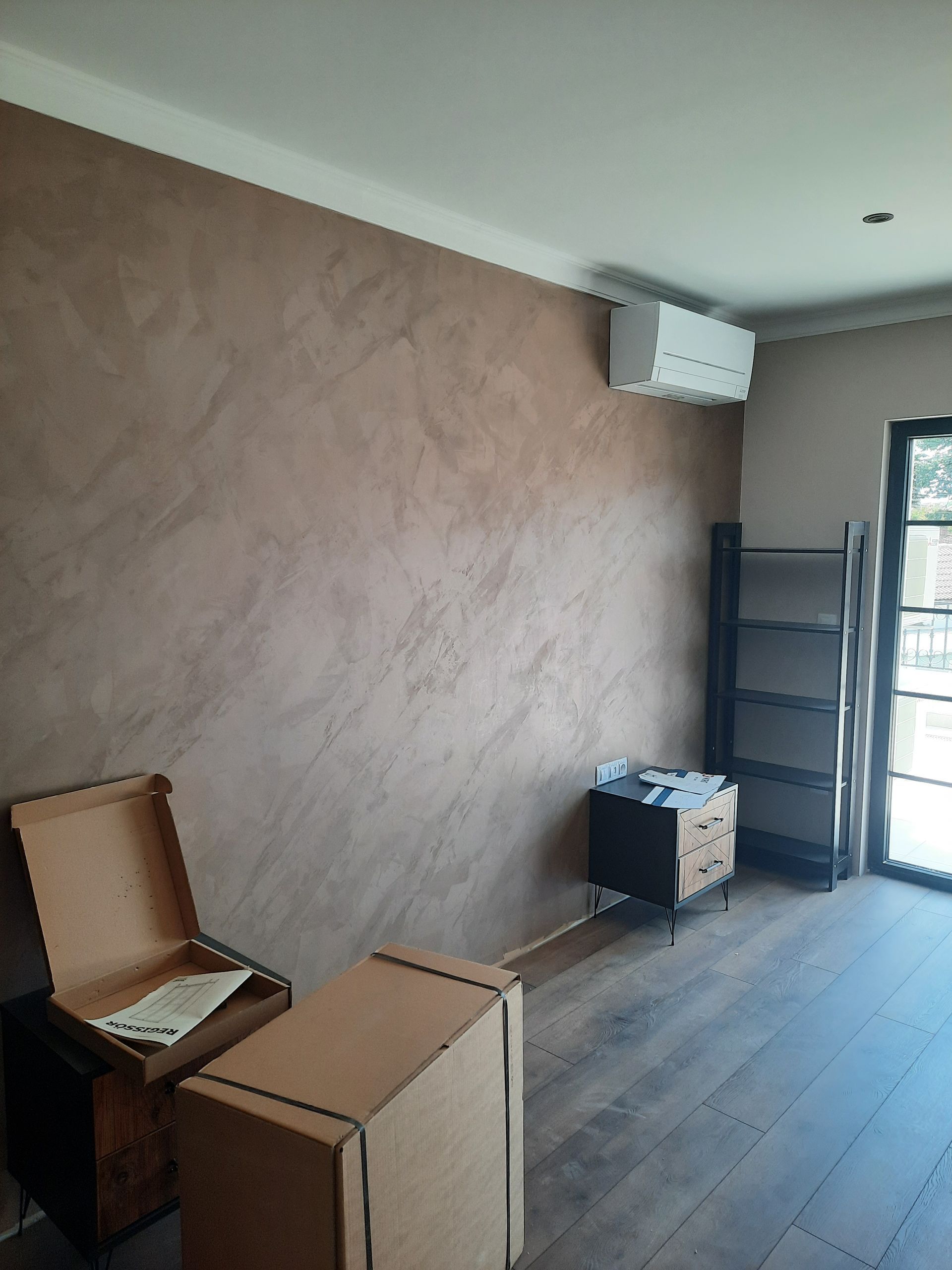 Habitación con pared texturizada marrón, aire acondicionado, suelo de madera y muebles.