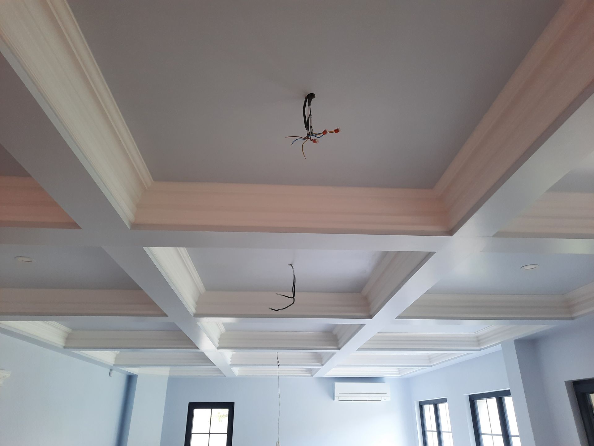 Techo artesonado blanco con molduras, cableado y paredes azul claro.