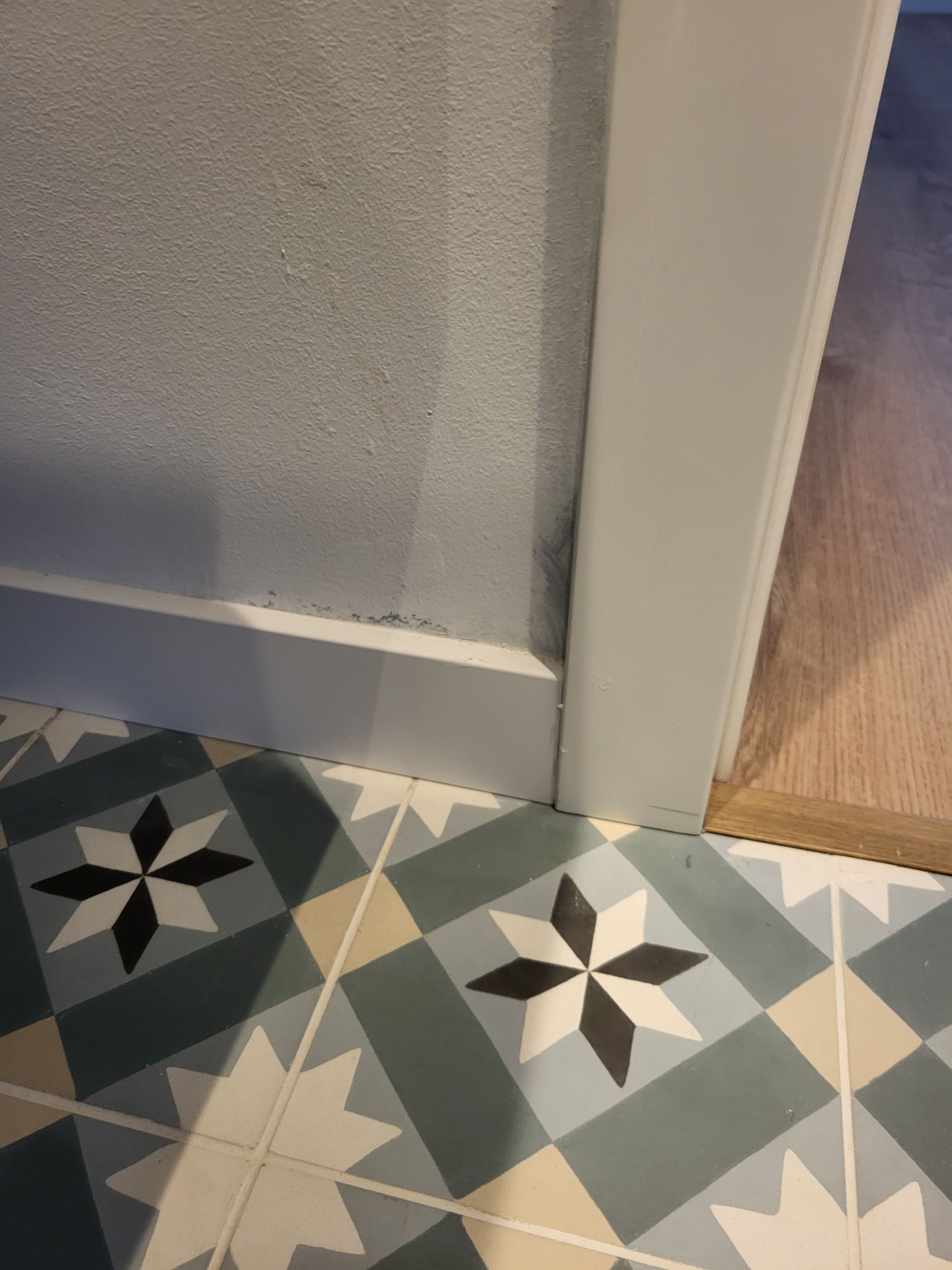 Primer plano de un panel de vidrio esmerilado enmarcado en blanco, con baldosas estampadas en el suelo.