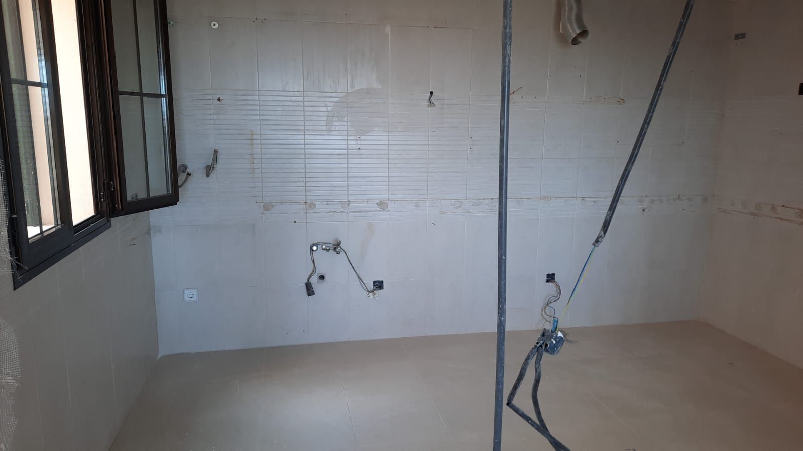 Habitación interior con paredes sin terminar y cableado eléctrico. Ventana visible en el lado izquierdo.
