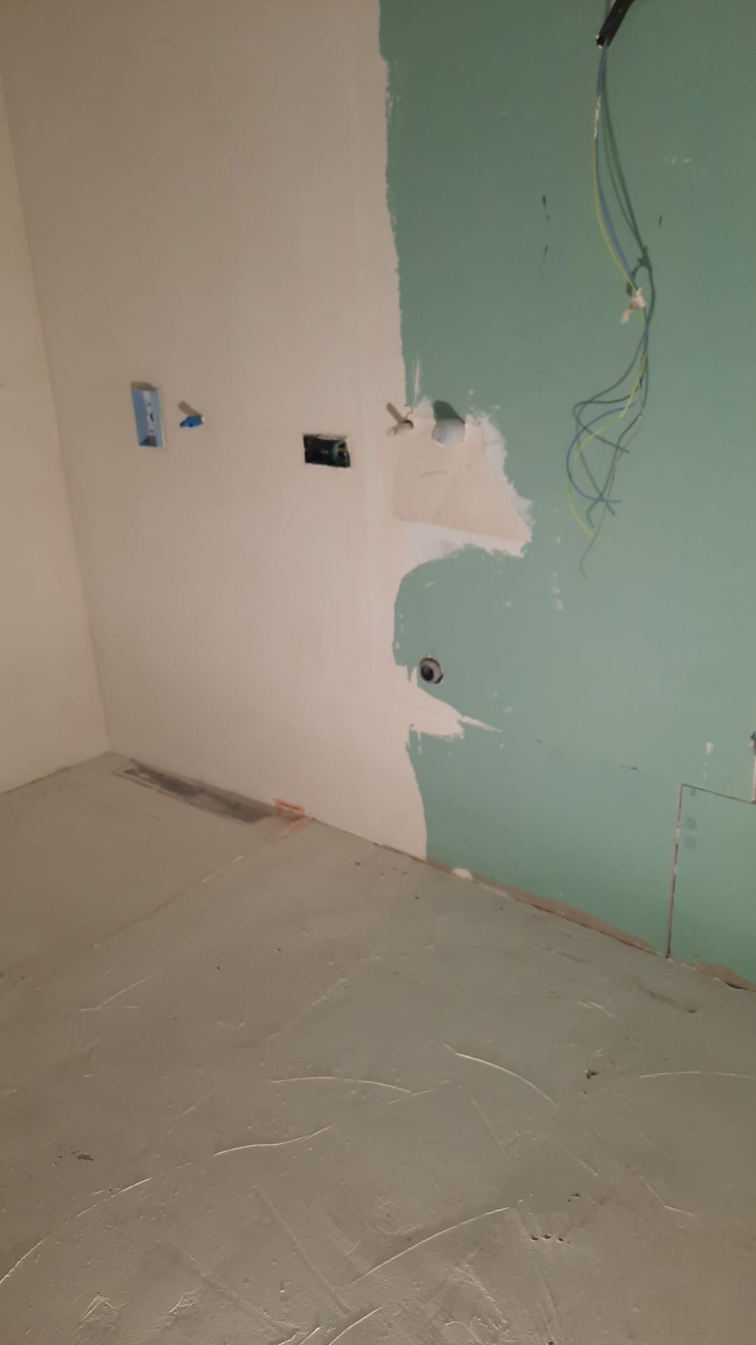 Habitación en construcción con paneles de yeso verdes parcialmente cubiertos de yeso blanco