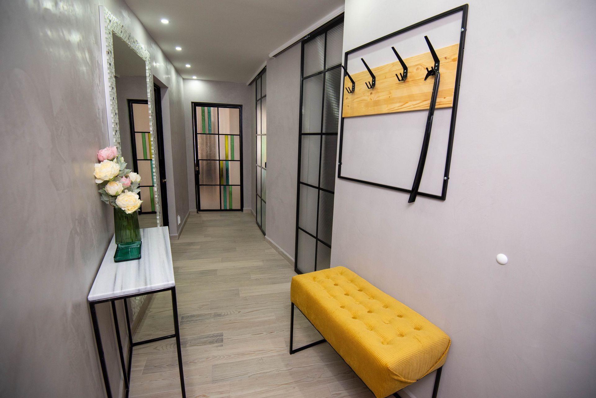 Pasillo estrecho con paredes grises y suelo de madera clara. 