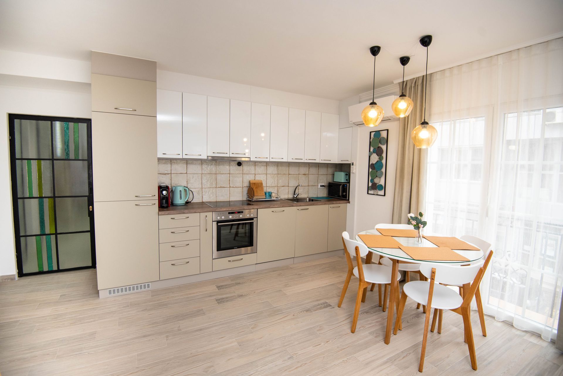 Cocina y comedor modernos con suelos de madera clara, armarios y una mesa puesta para seis personas.