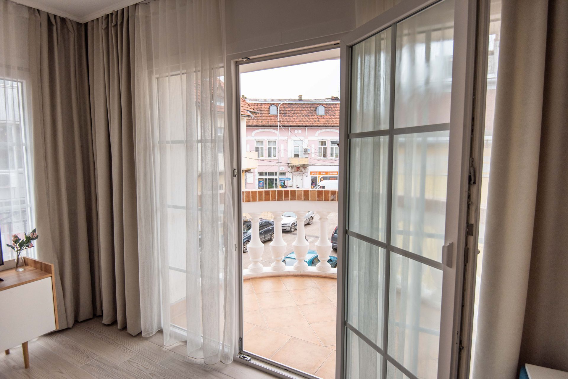 Vista desde el balcón: Puerta de cristal abierta, cortinas color beige,