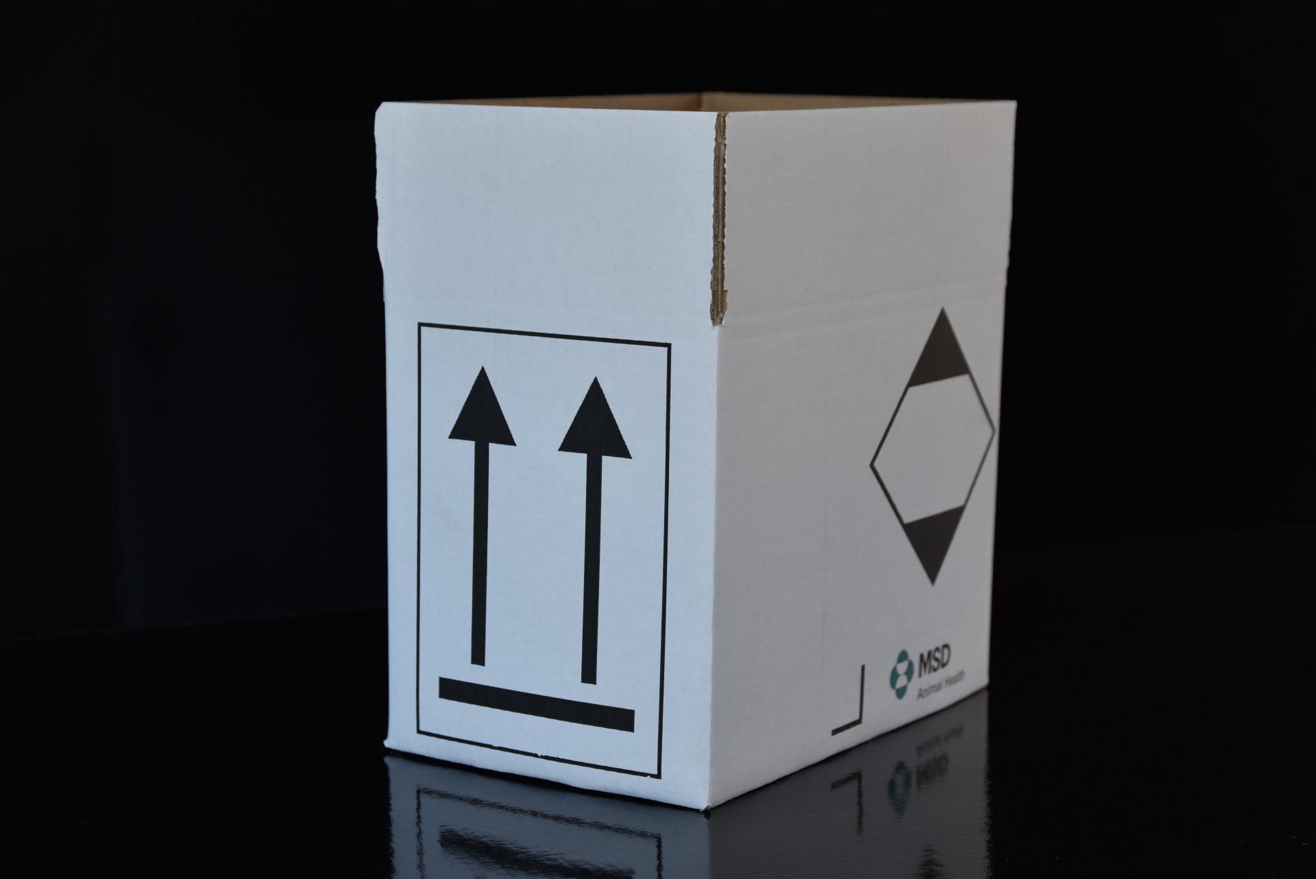 Boîte en carton blanc avec des flèches pointant vers le haut et un symbole de danger en forme de losange.