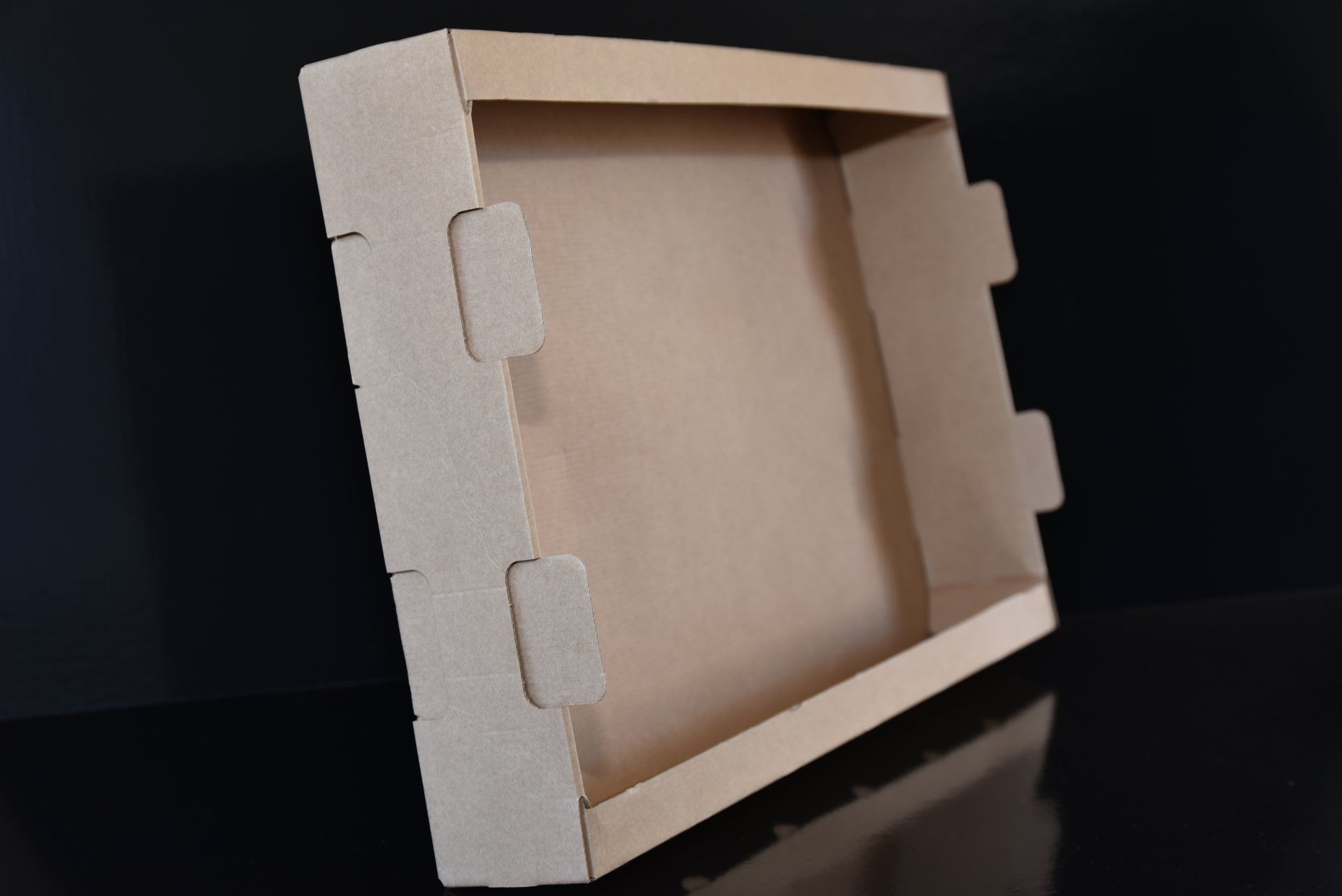 Plateau en carton ouvert, à côtés crantés ; sur fond noir.