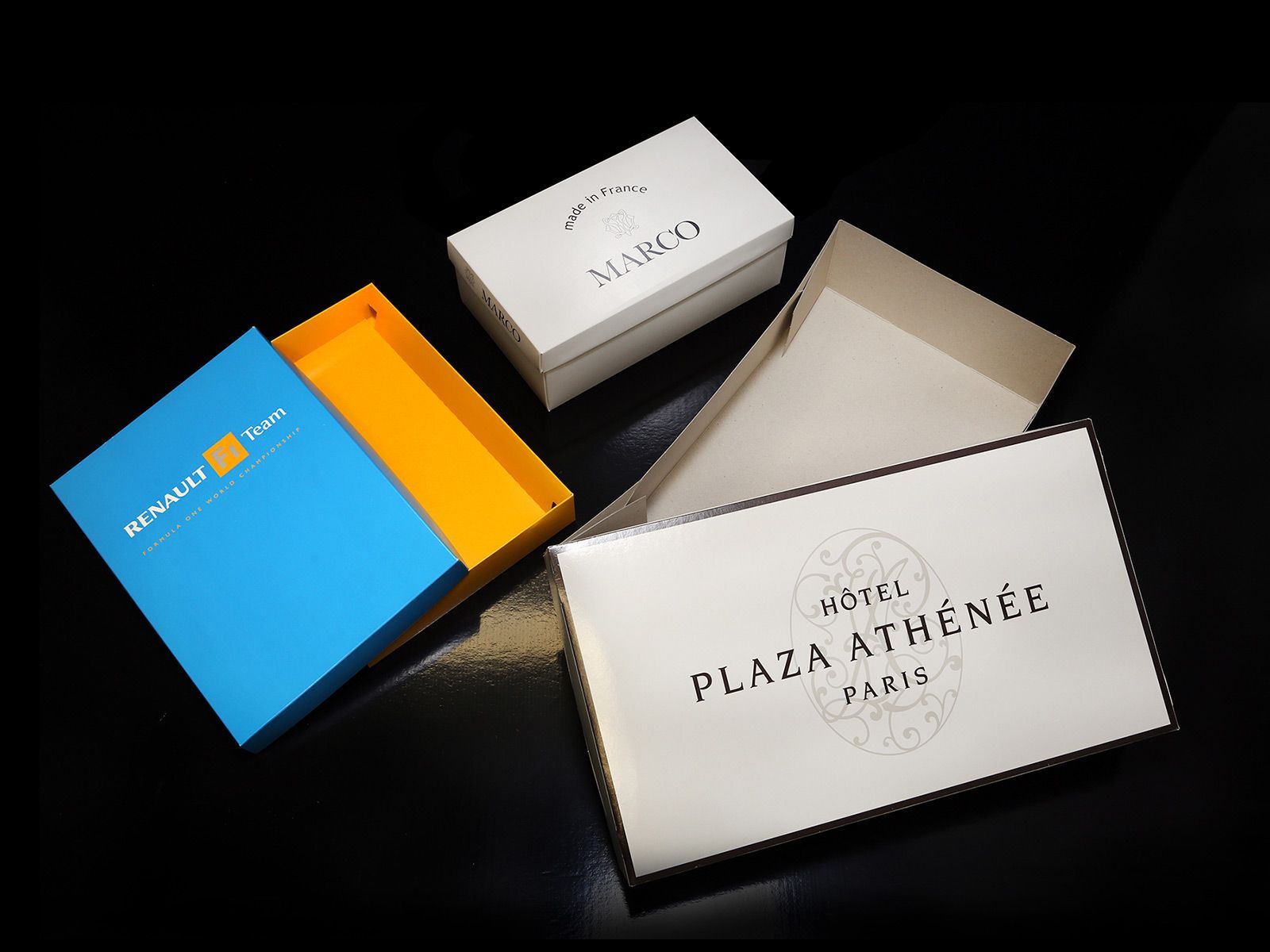 Quatre boîtes ouvertes de couleurs et de marques différentes sur une surface noire.