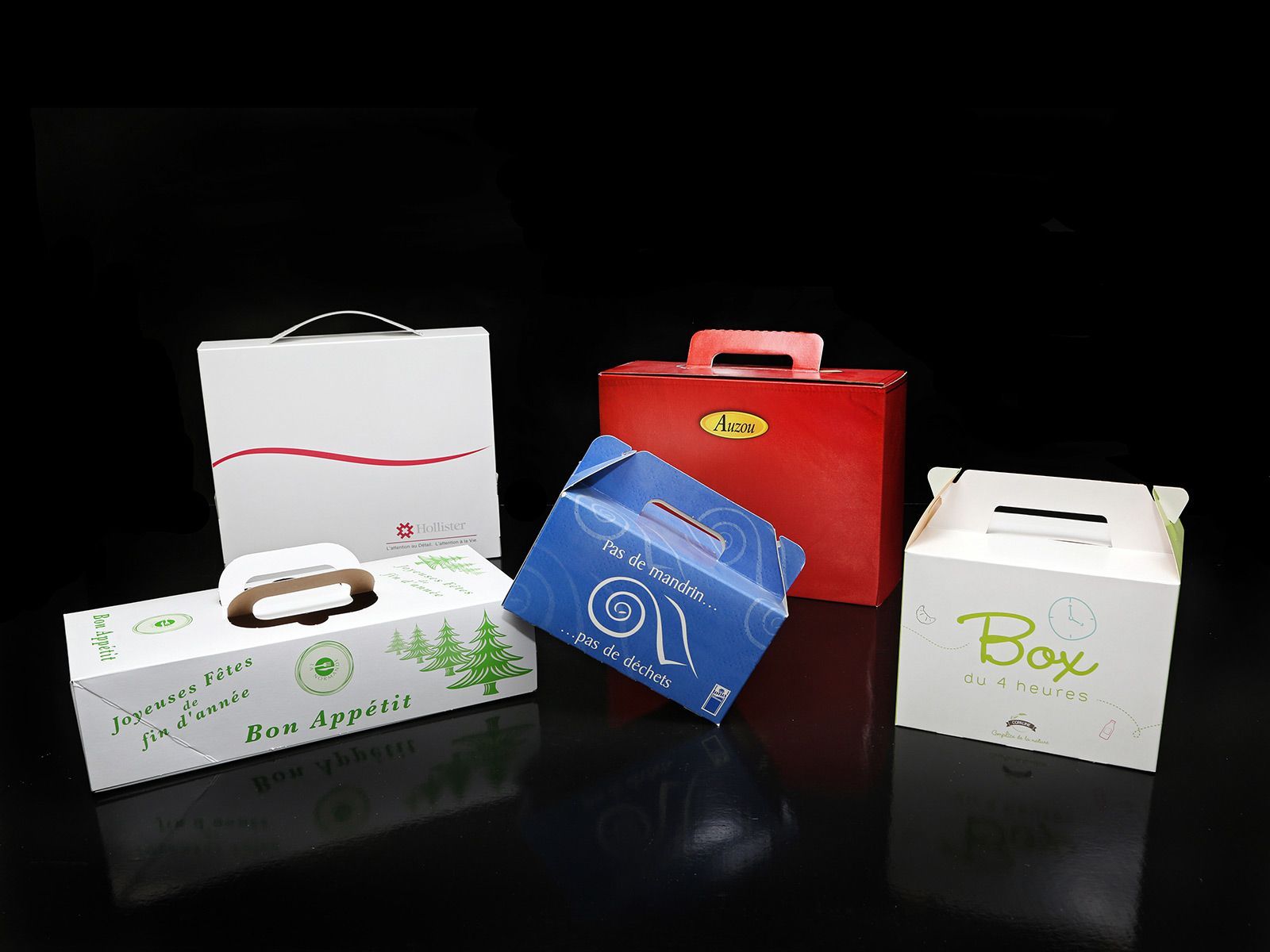 Diverses boîtes colorées avec poignées sur une surface noire réfléchissante.