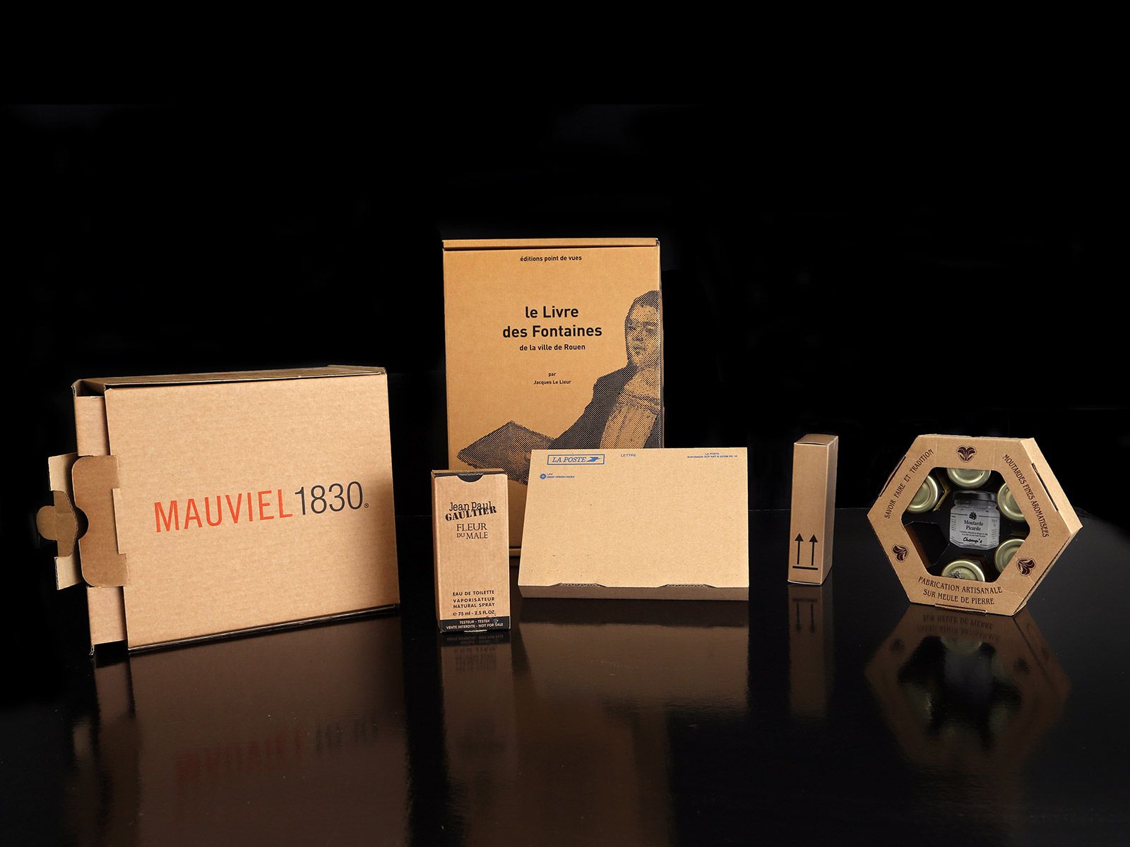 Des boîtes d'emballage en carton de différentes tailles sur fond noir. Certaines comportent des textes et des images imprimés.