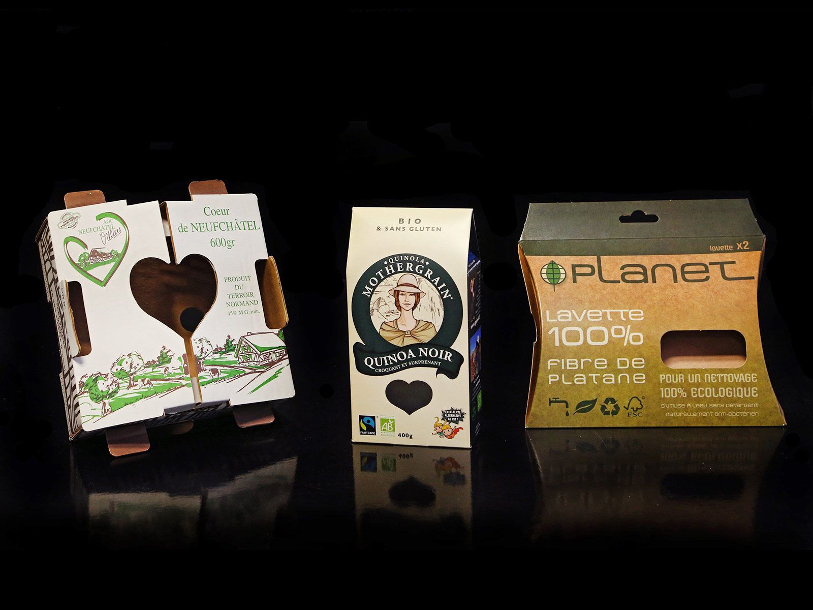 Trois emballages de produits en carton sur fond noir.