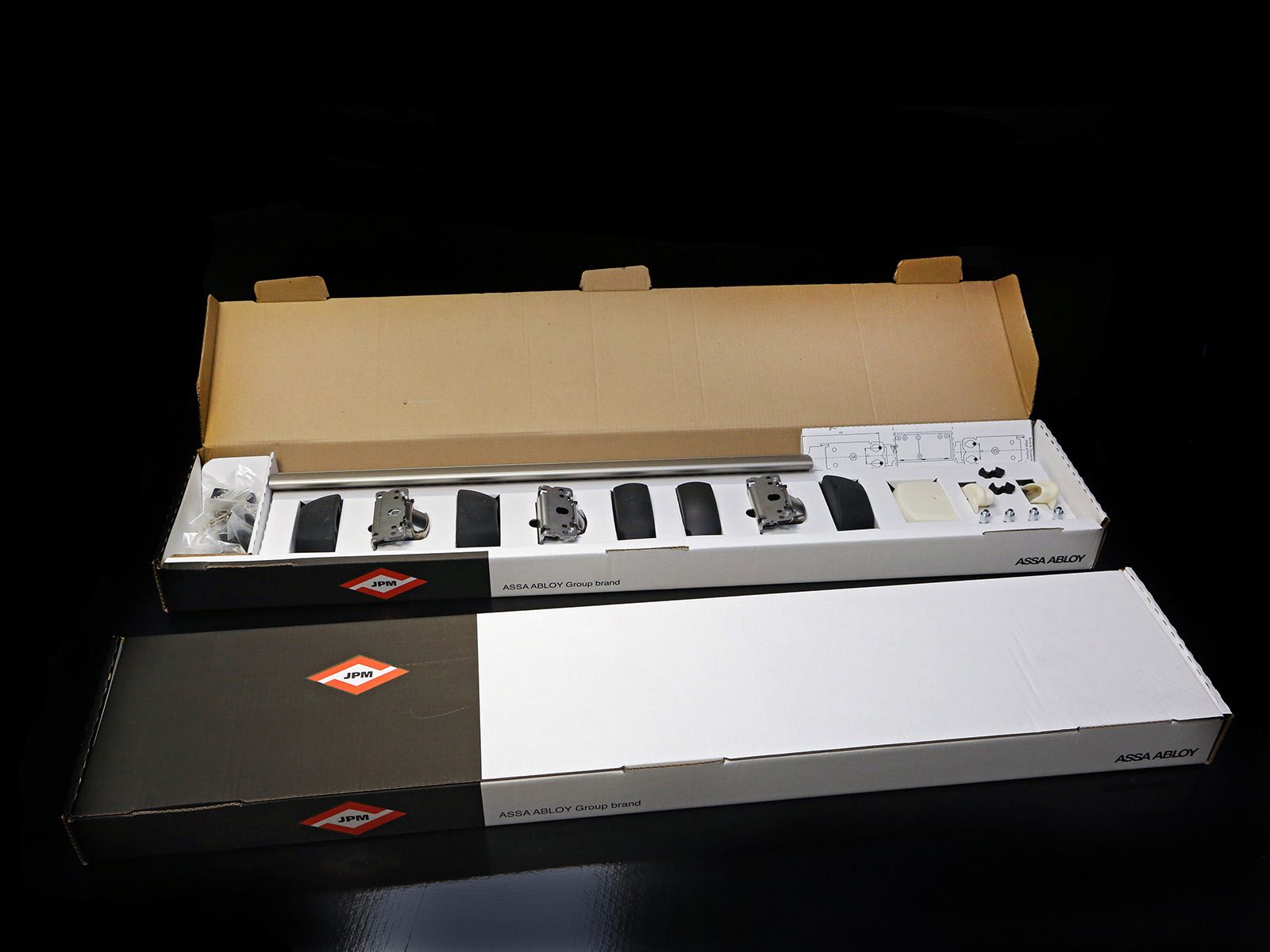 Boîte contenant le canon d'une arme à feu et ses pièces disposées sur une surface noire.