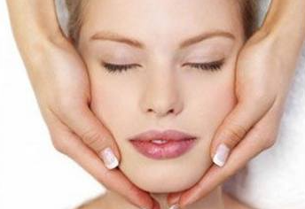 Una mujer está recibiendo un masaje facial con los ojos cerrados.