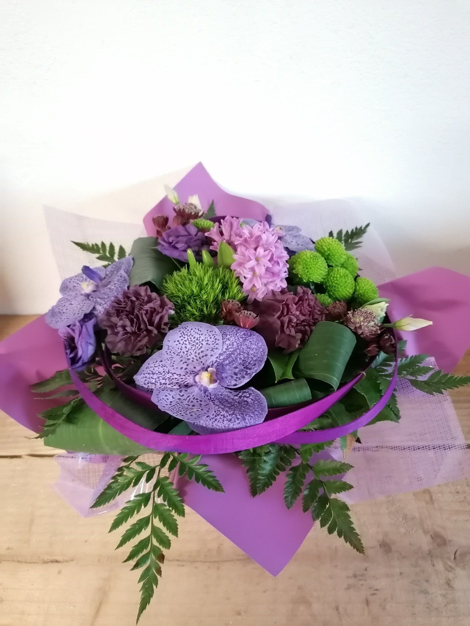 Un bouquet de fleurs violettes agrementé de quelques feuilles de plantes vertes