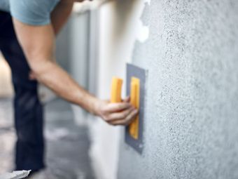 Truelle tenue par un artisan pour appliquer l'enduit sur un mur