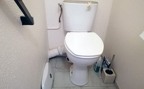 Des toilettes blanches dans une petite pièce