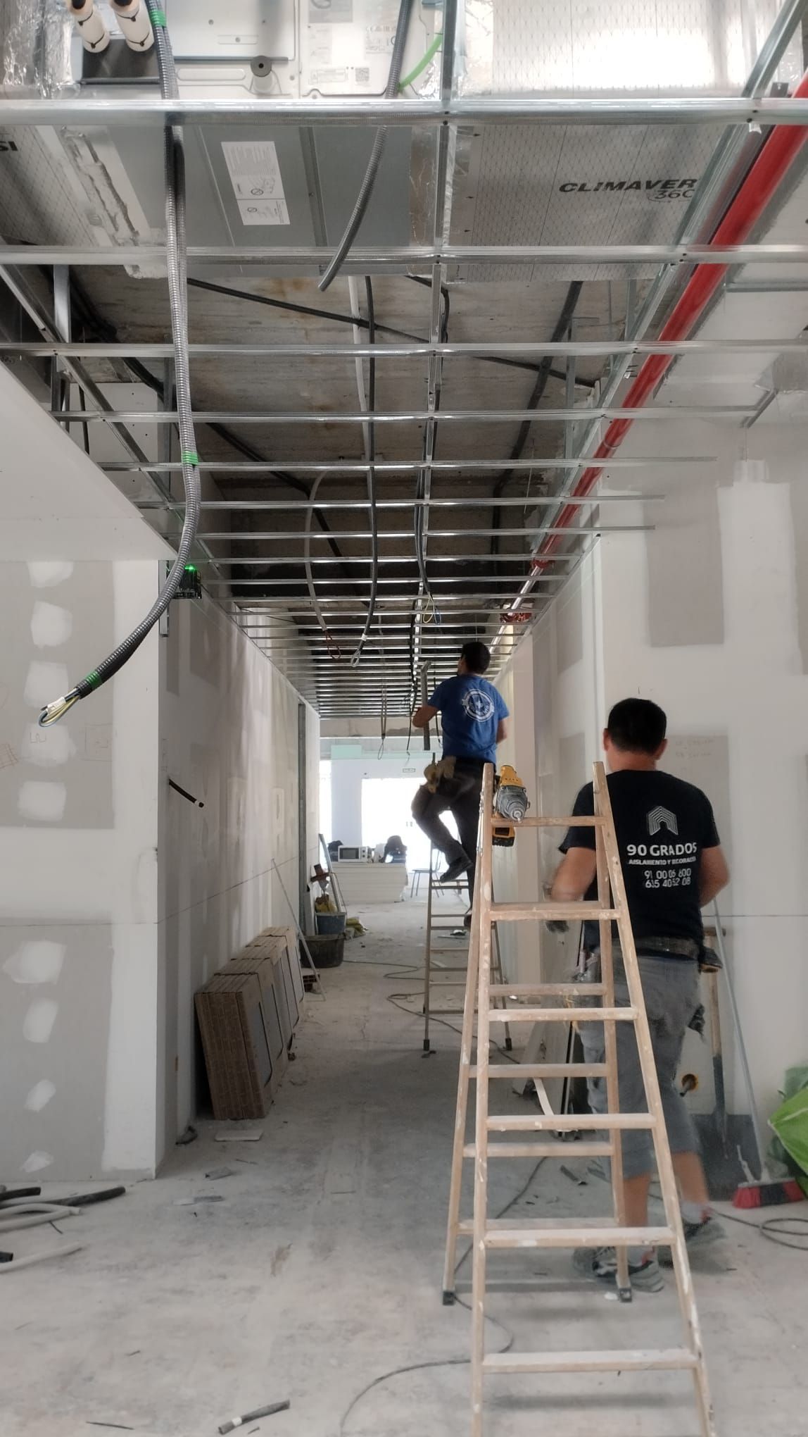 Una pared con material insonorizante y una gran lámina blanca adherida. El material insonorizante es oscuro y tiene texto claro.