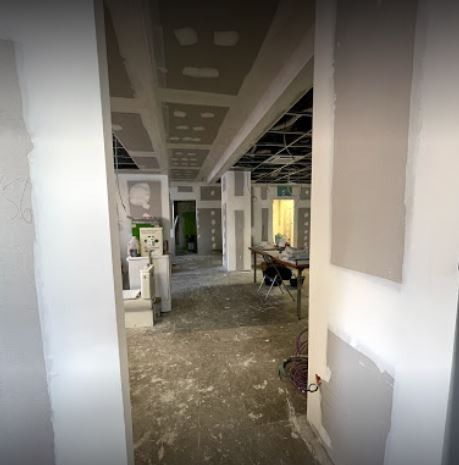 Interior en construcción: vista a través de las puertas hacia las paredes y el techo sin terminar. Se ven los montantes y el cableado expuesto.