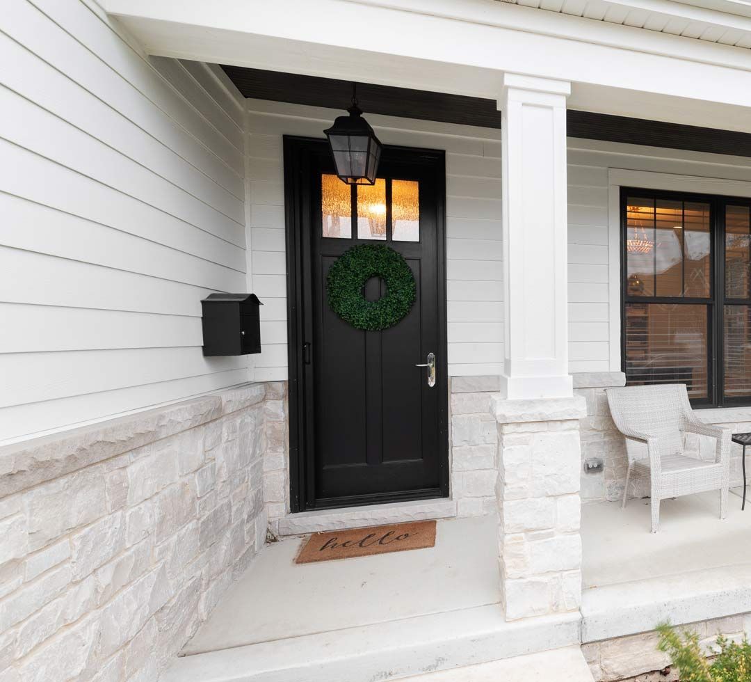 Porte d'entrée en bois foncé et perron en bois blanc