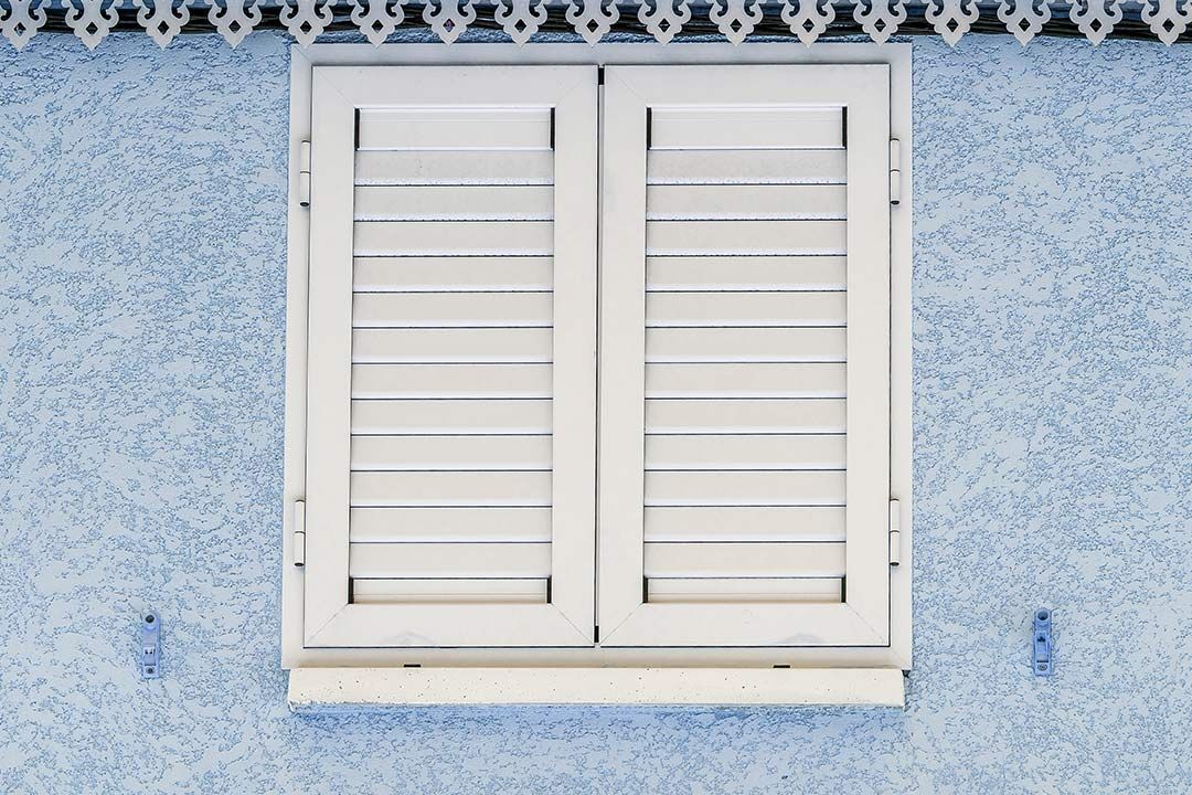 Volets battants blancs sur façade bleu clair