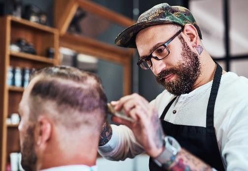 Barbier en train de tailler la barbe d'un de ses clients
