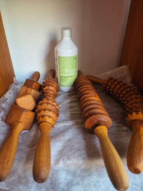 Strumenti per massaggi in legno e una bottiglia su uno scaffale.