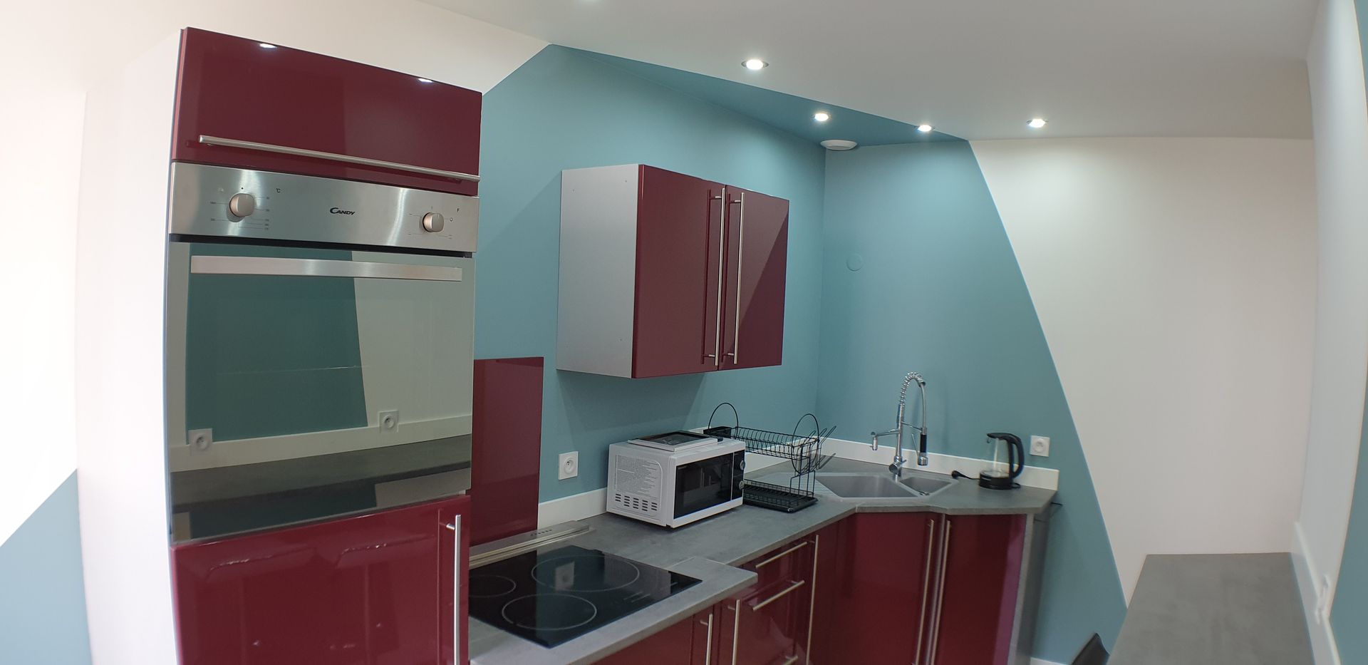 Cuisine moderne avec des meubles bordeaux et murs bleu-vert